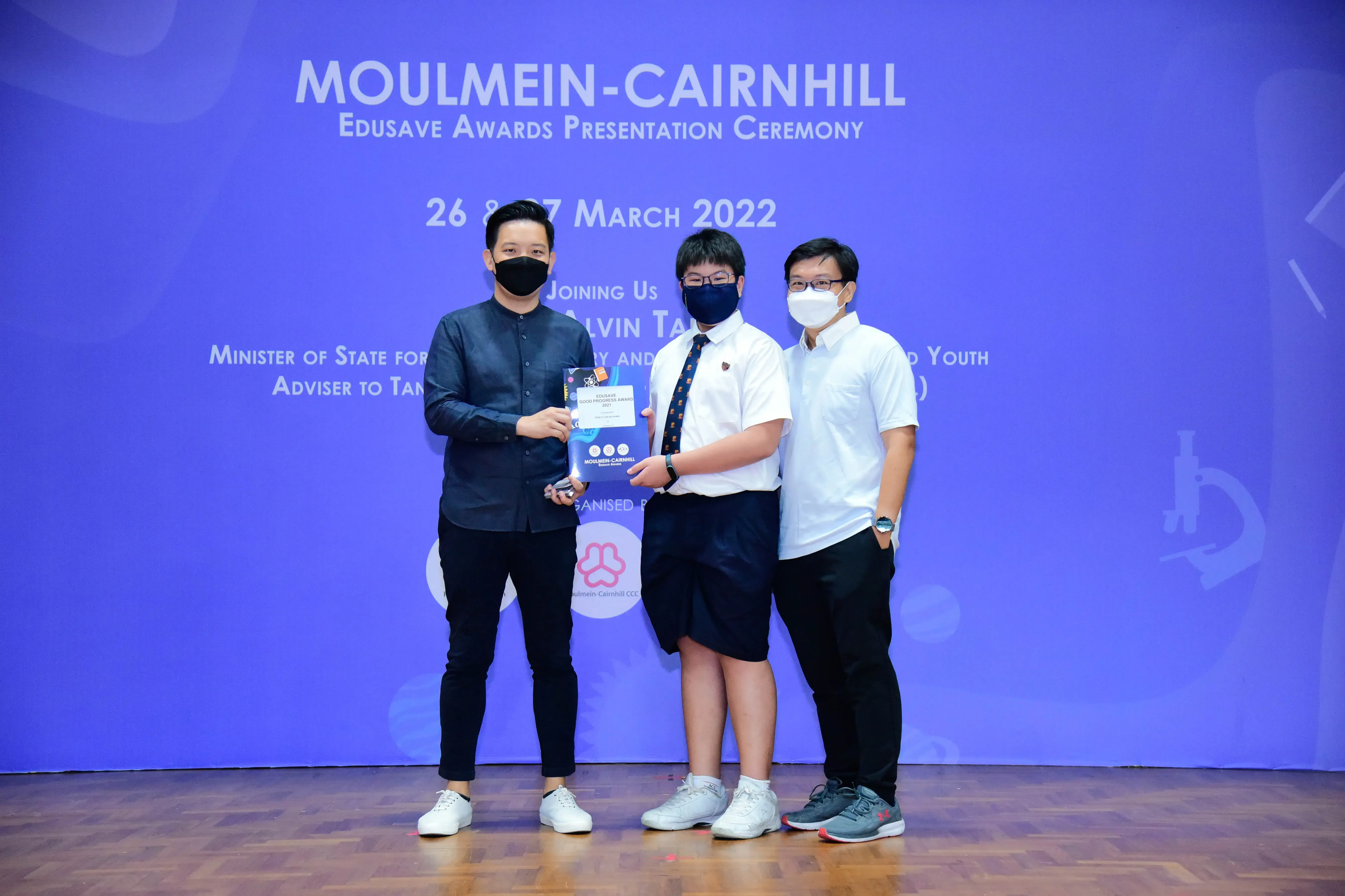 Three masked people pose together holding an award at the Moulmein-Cairnhill Edusave Awards Ceremony, March 2022.