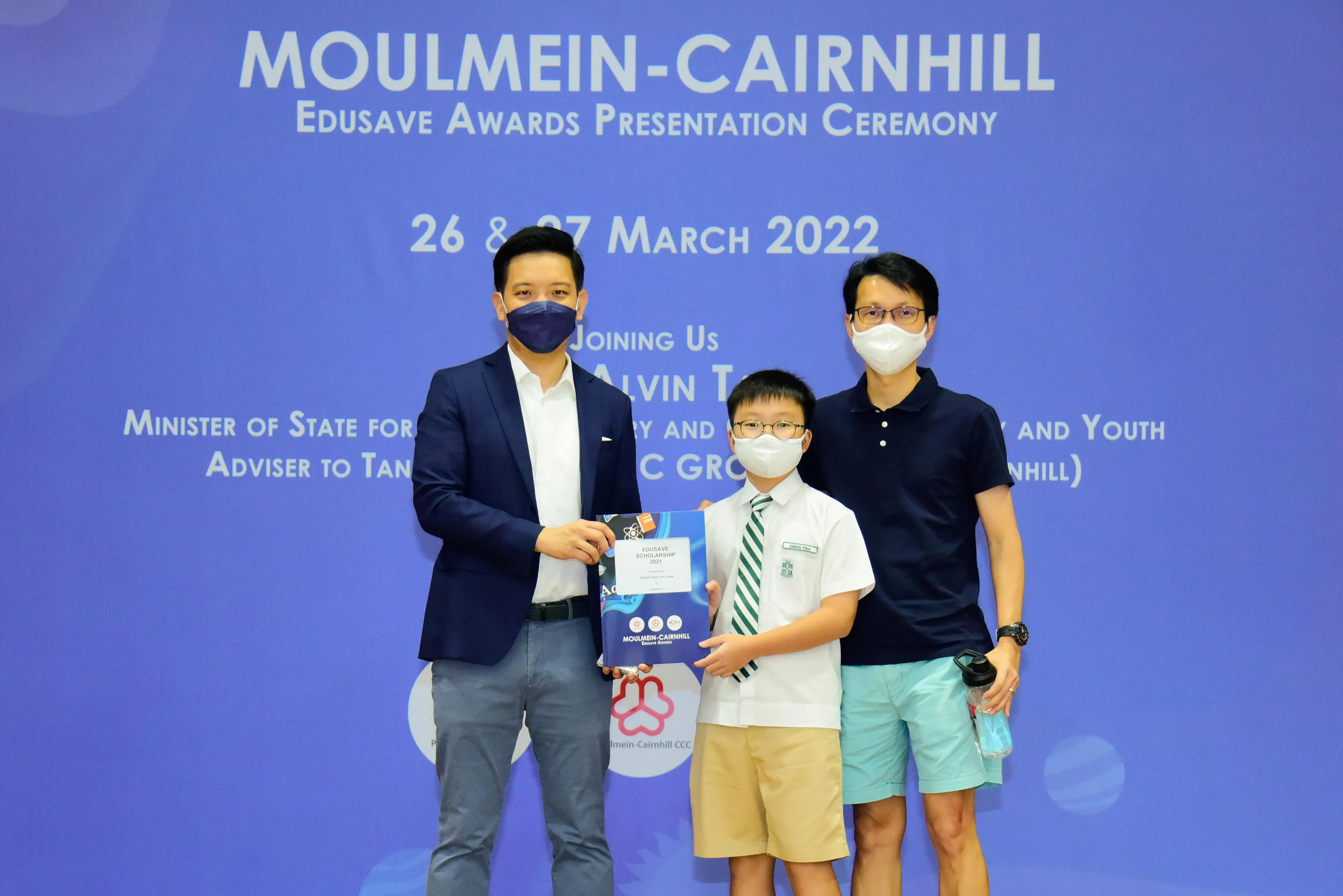 Three masked people pose at the Moulmein-Cairnhill Edusave Awards Presentation Ceremony, March 2022.
