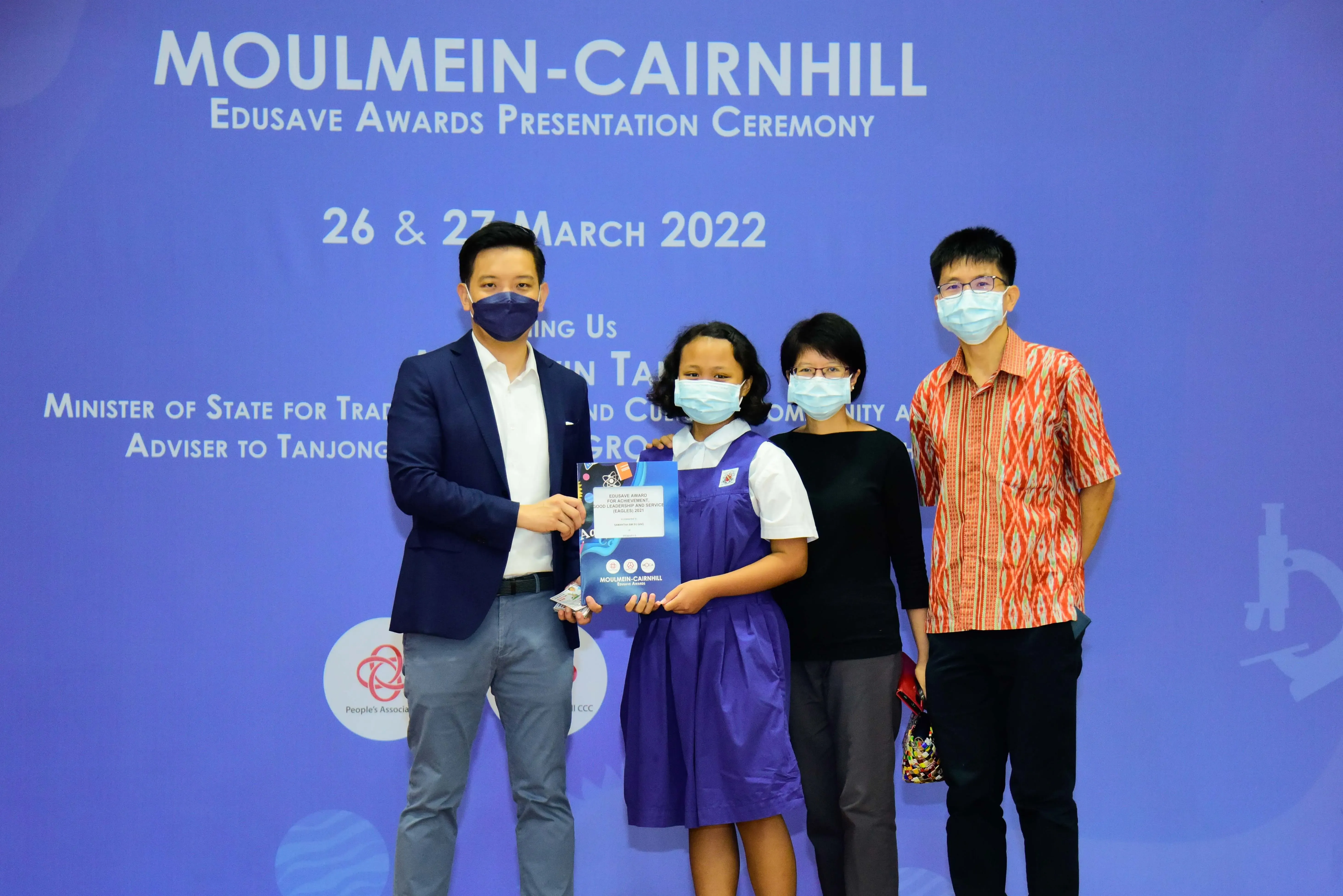 Four masked people pose at the Moulmein-Cairnhill Edusave Awards Presentation Ceremony on 26-27 March 2022.
