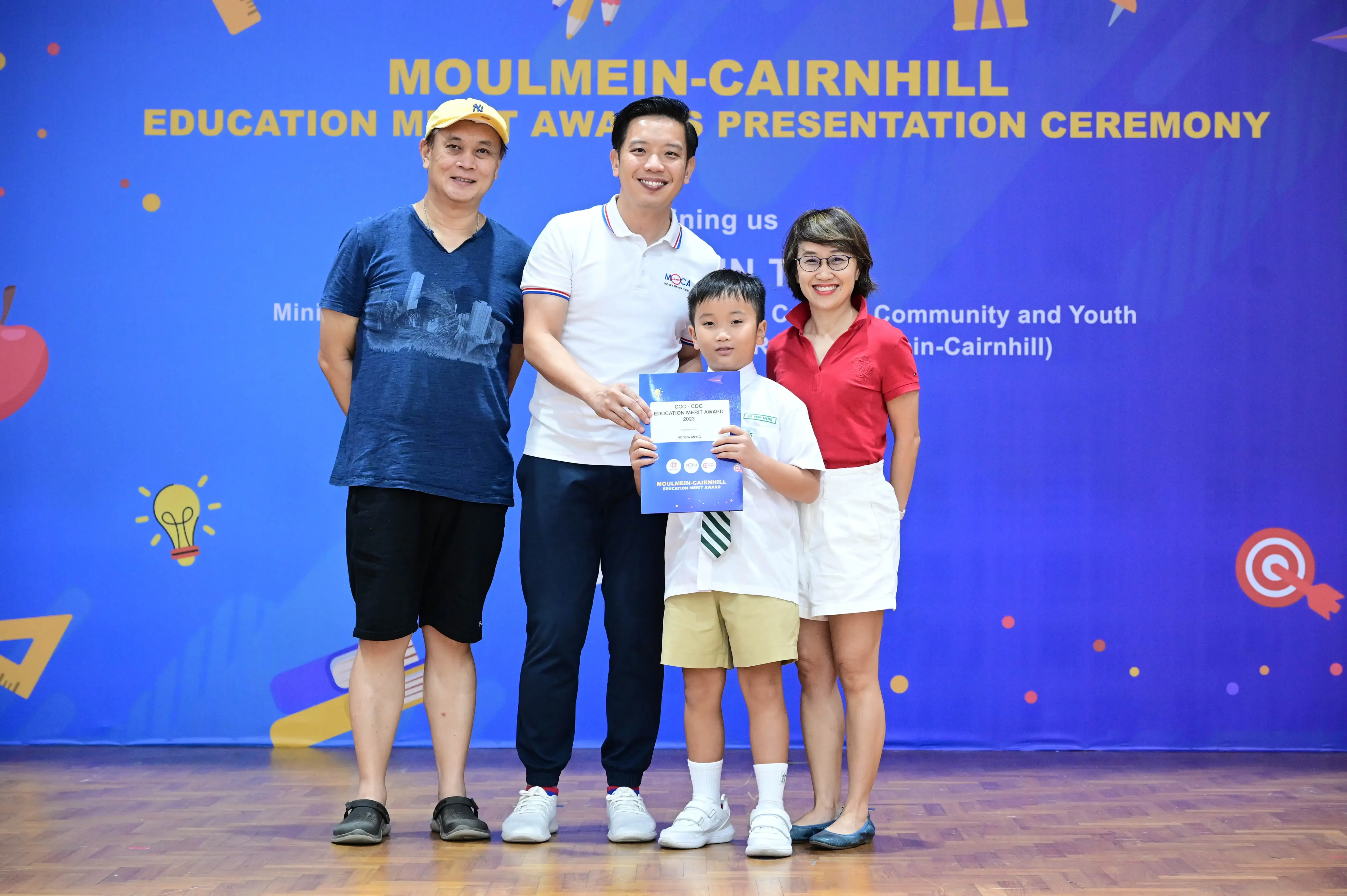 Three adults and a boy holding a certificate pose at the Moulmein-Cairnhill Education Merit Awards Presentation Ceremony.