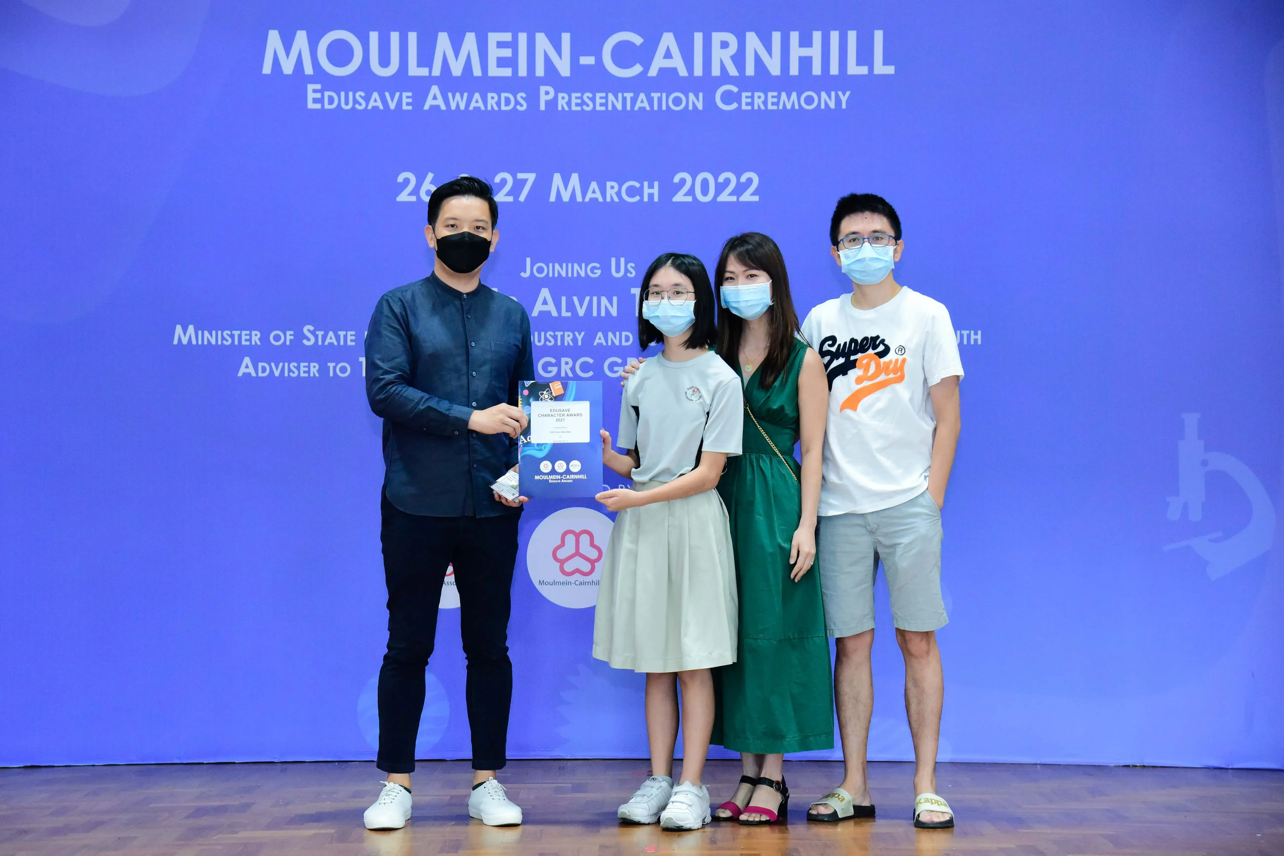 Four masked people pose at the Moulmein-Cairnhill Edusave Awards Presentation Ceremony on March 26-27, 2022.