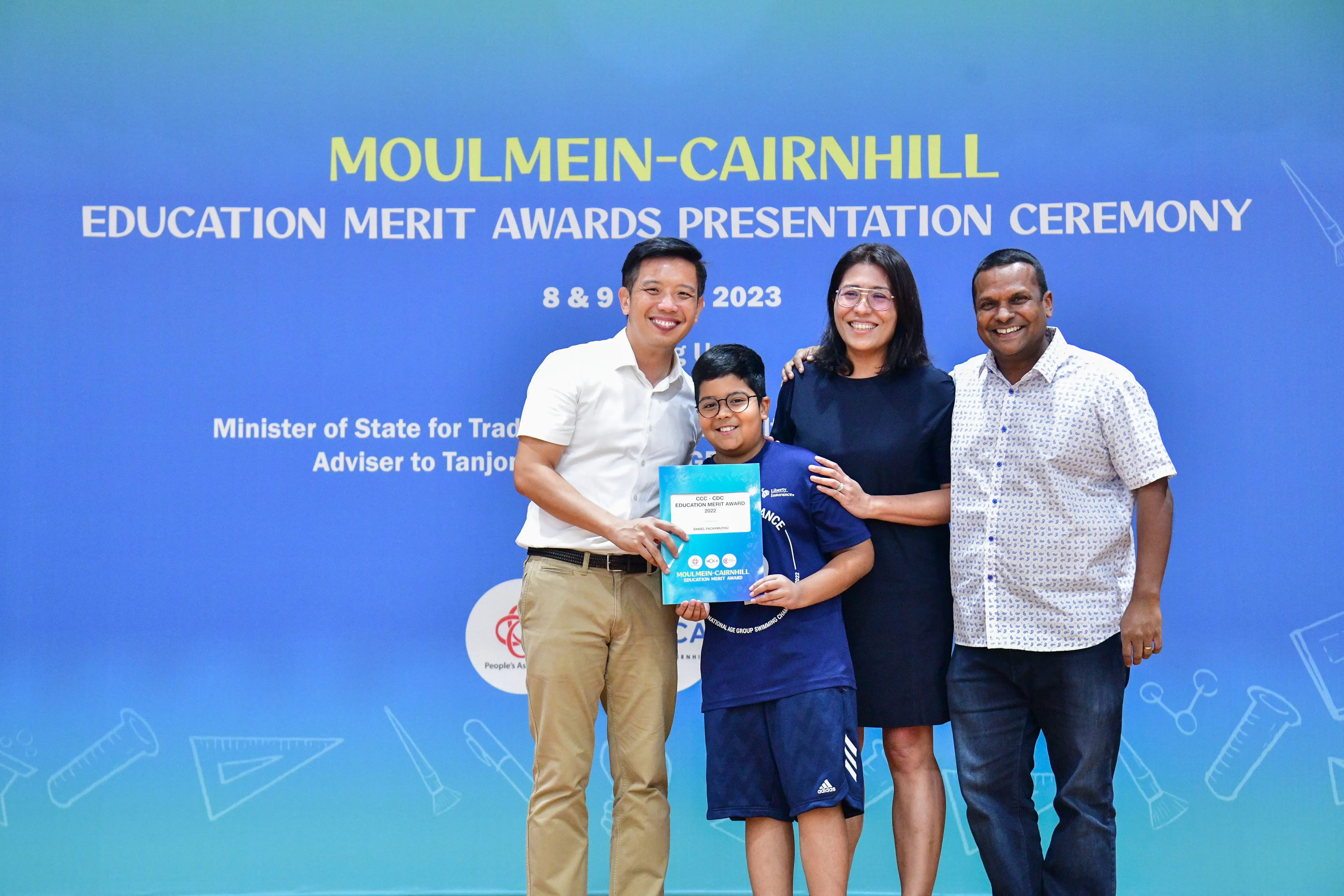 Four people smile holding an award certificate at the Moulmein-Cairnhill Education Merit Awards Ceremony 2023.
