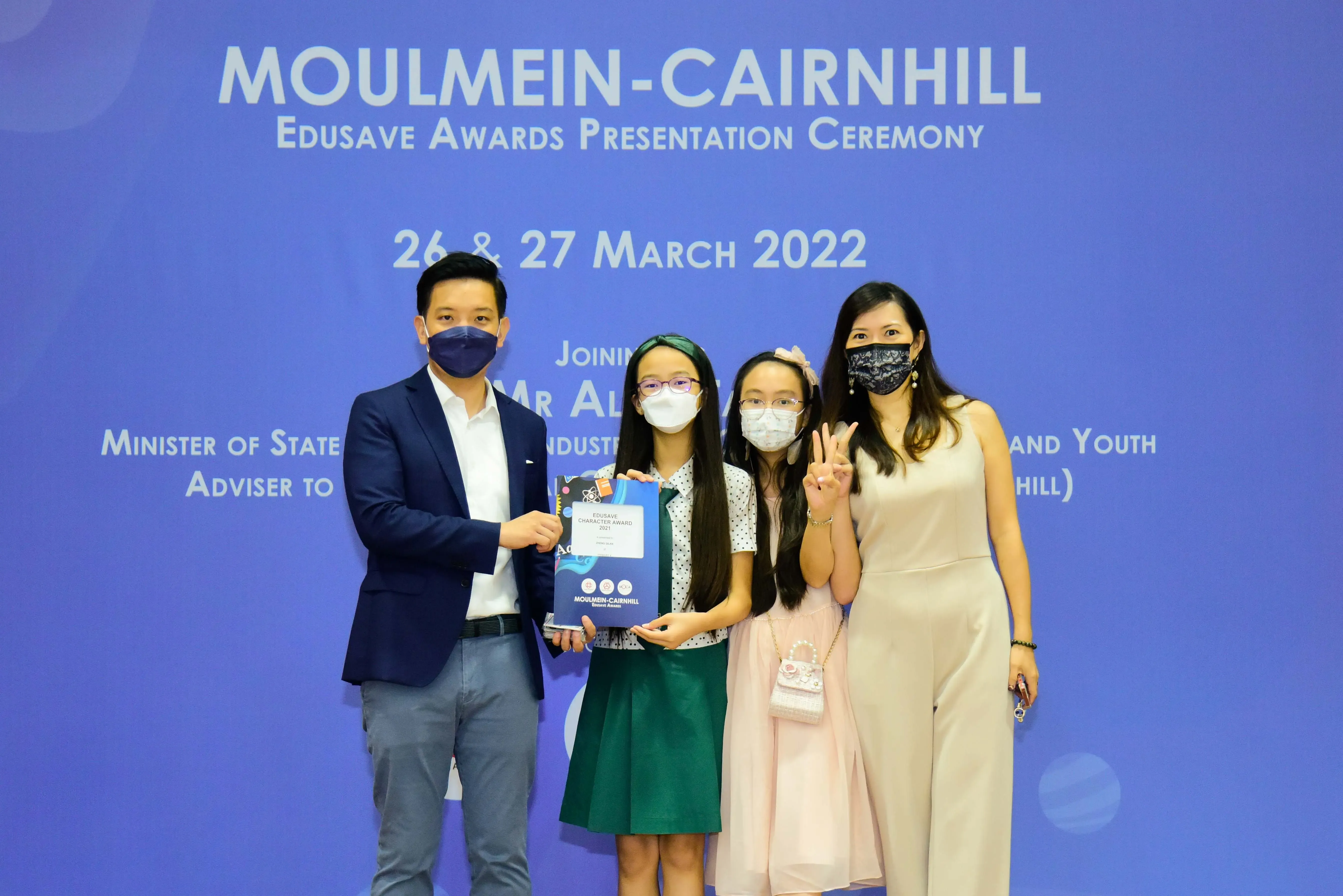 Four masked people pose at the Moulmein-Cairnhill Edusave Awards Presentation Ceremony on 26-27 March 2022.