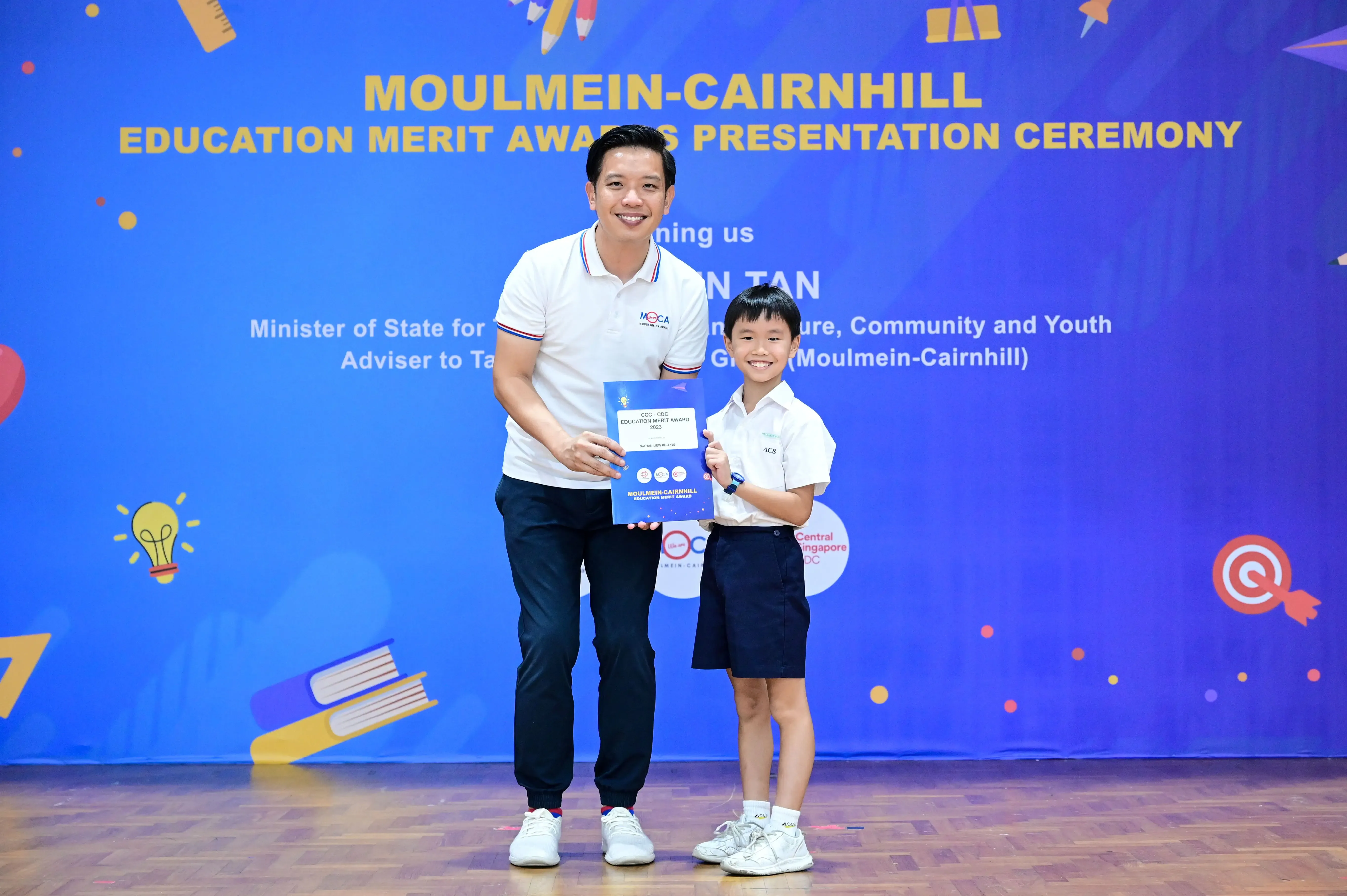 Man and young boy holding a certificate at Moulmein-Cairnhill Education Merit Awards Presentation Ceremony.