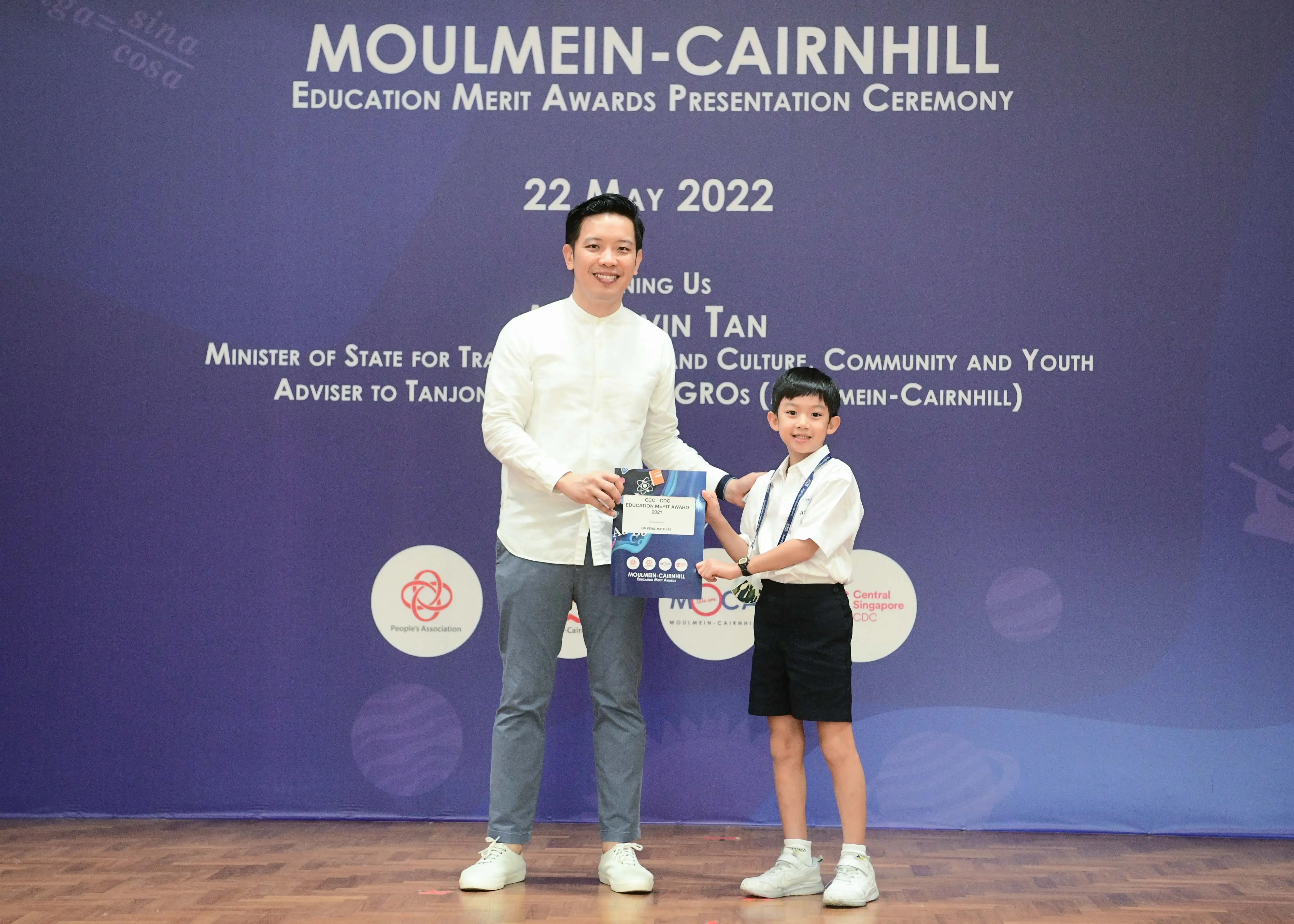 A man and a young boy hold an award certificate at the Moulmein-Cairnhill Education Merit Awards on 22 May 2022.