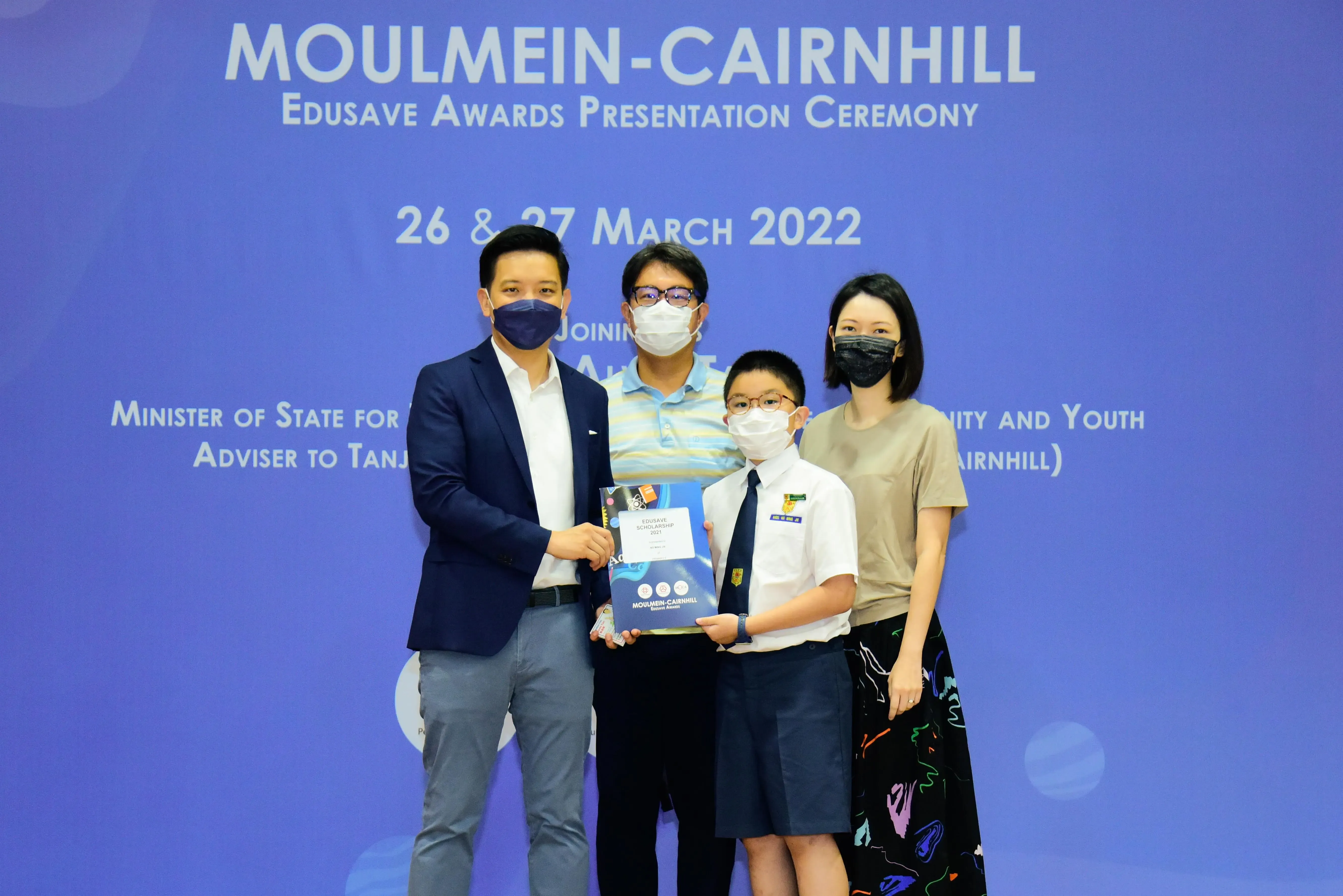 Four masked people pose at the Moulmein-Cairnhill Edusave Awards Presentation Ceremony on 26-27 March 2022.