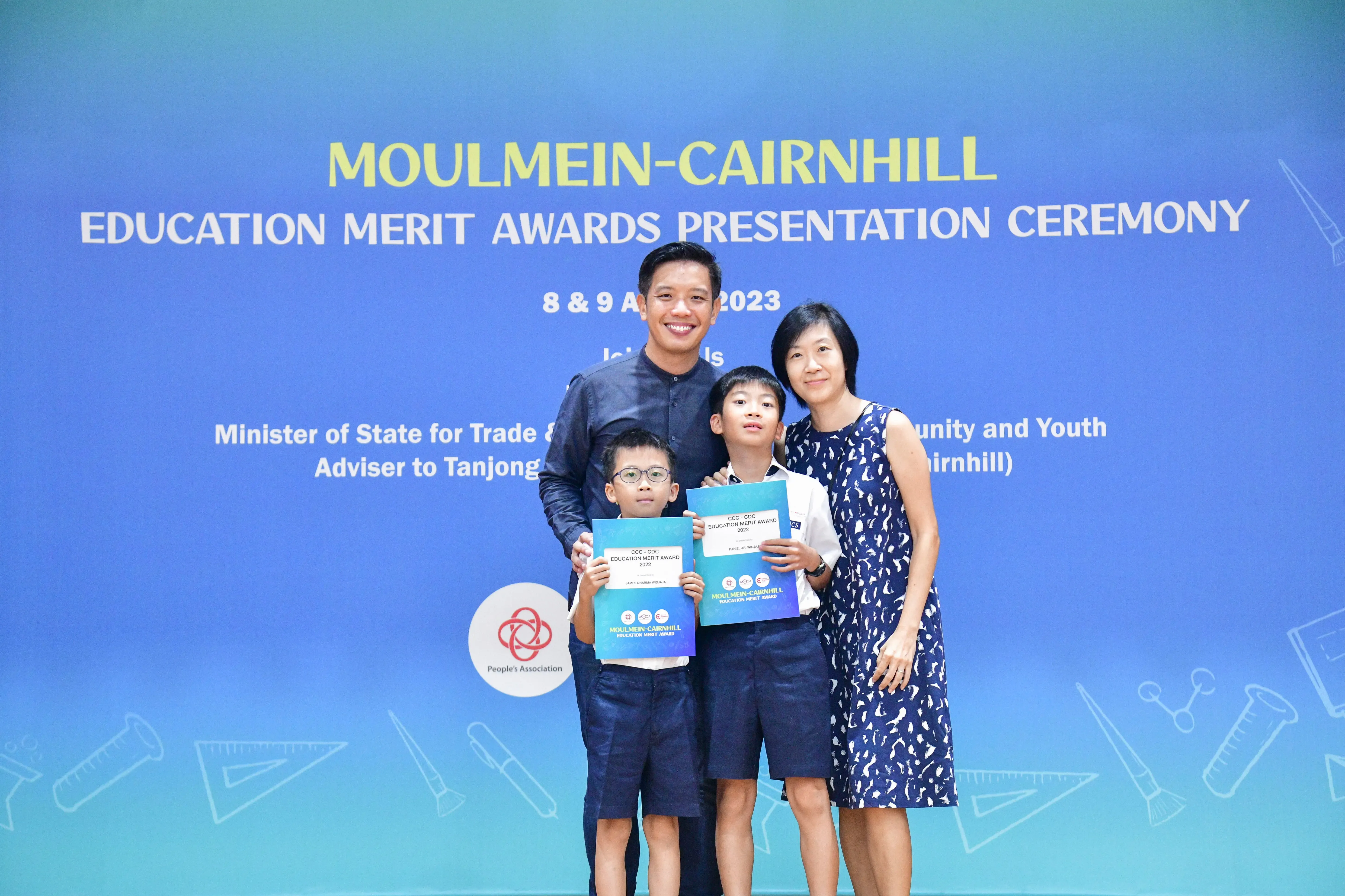 Two adults and two boys pose holding award certificates at the Moulmein-Cairnhill Education Merit Awards 2023.