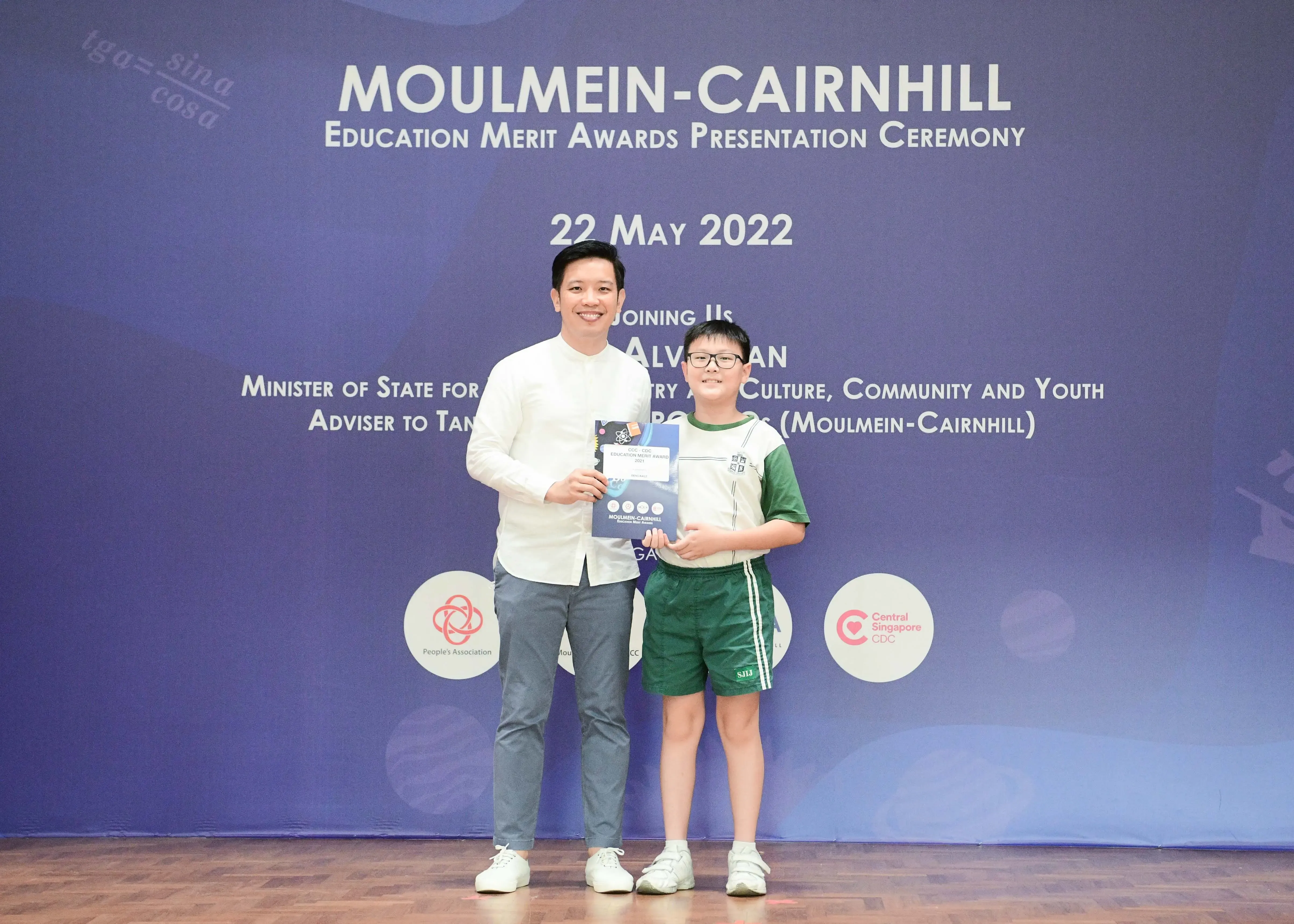 An adult and a young boy holding an award certificate at the Moulmein-Cairnhill Education Merit Awards on 22 May 2022.