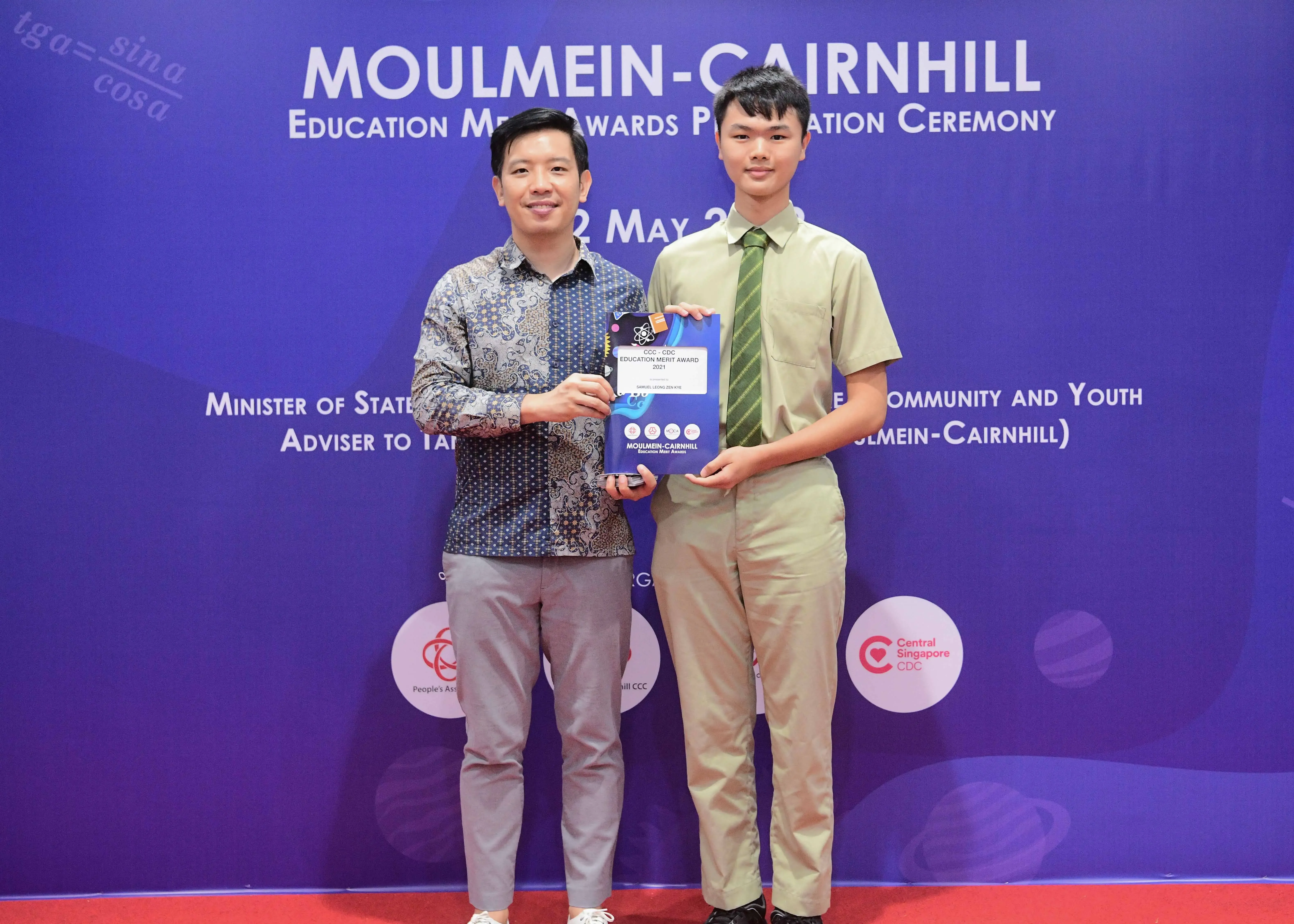 Two men pose holding an award plaque at the Moulmein-Cairnhill Education Merit Awards Presentation Ceremony.