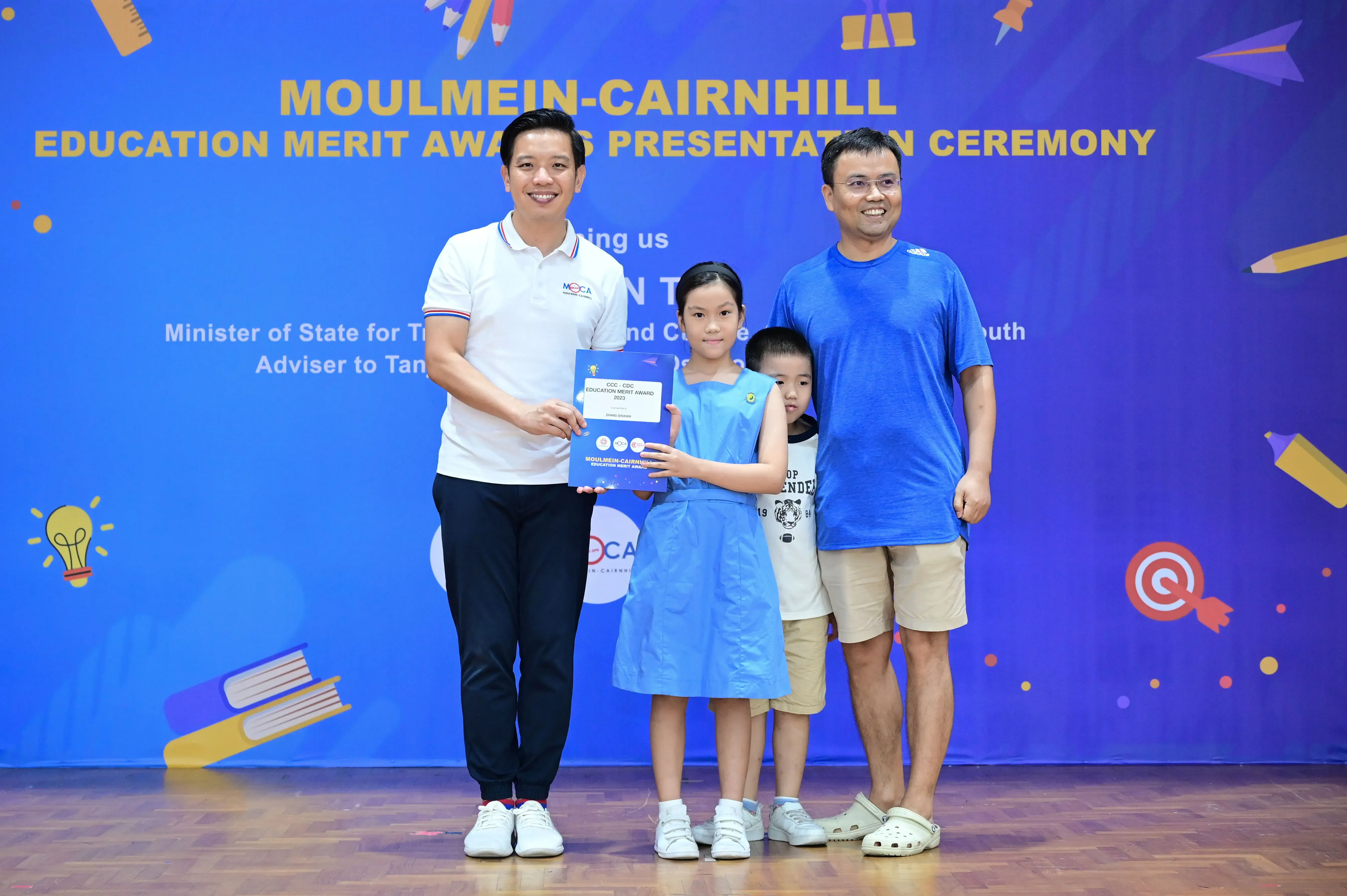 Two men and two children pose with a certificate at the Moulmein-Cairnhill Education Merit Awards Ceremony.