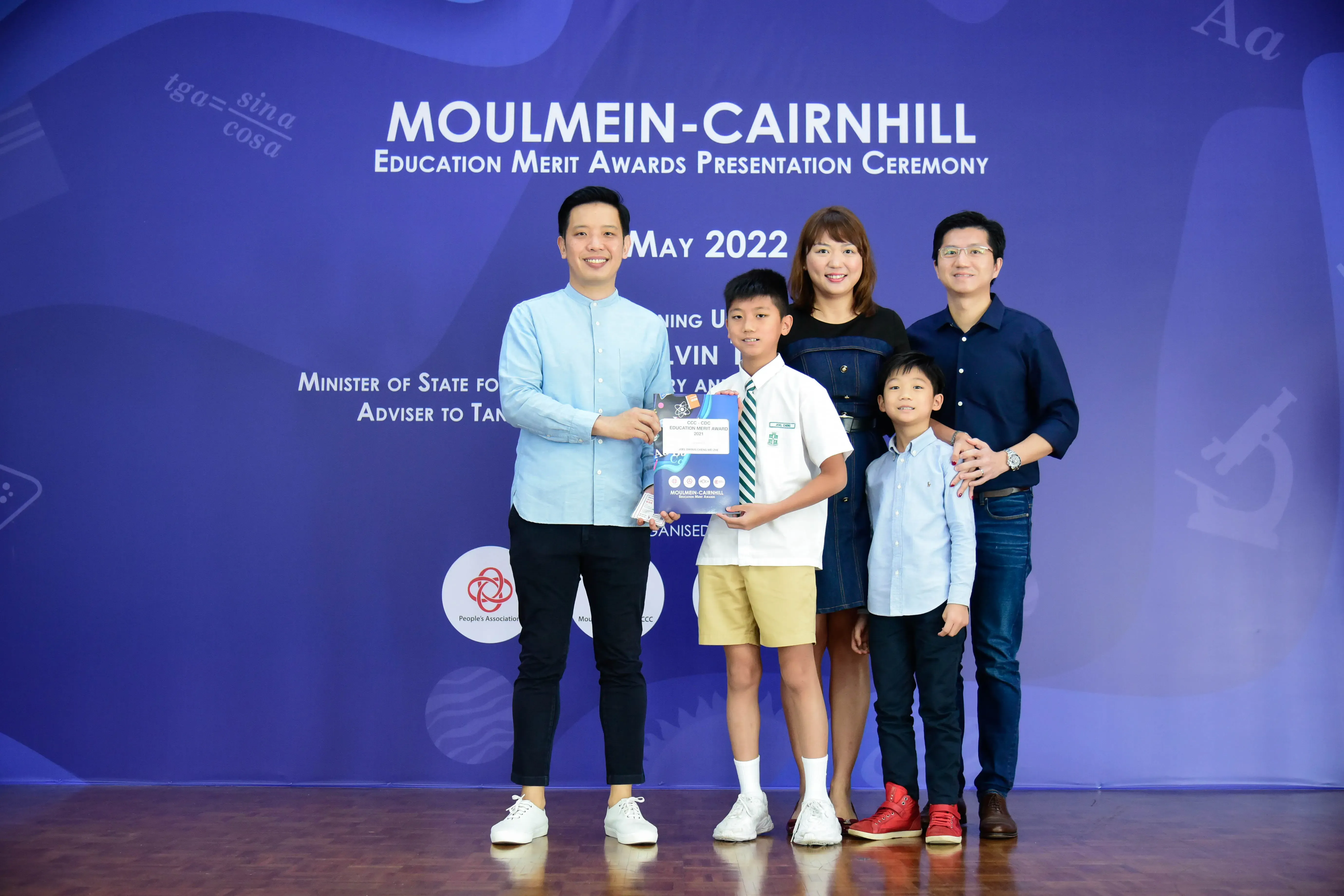 A boy receives an award certificate at the Moulmein-Cairnhill Education Merit Awards Ceremony, May 2022.