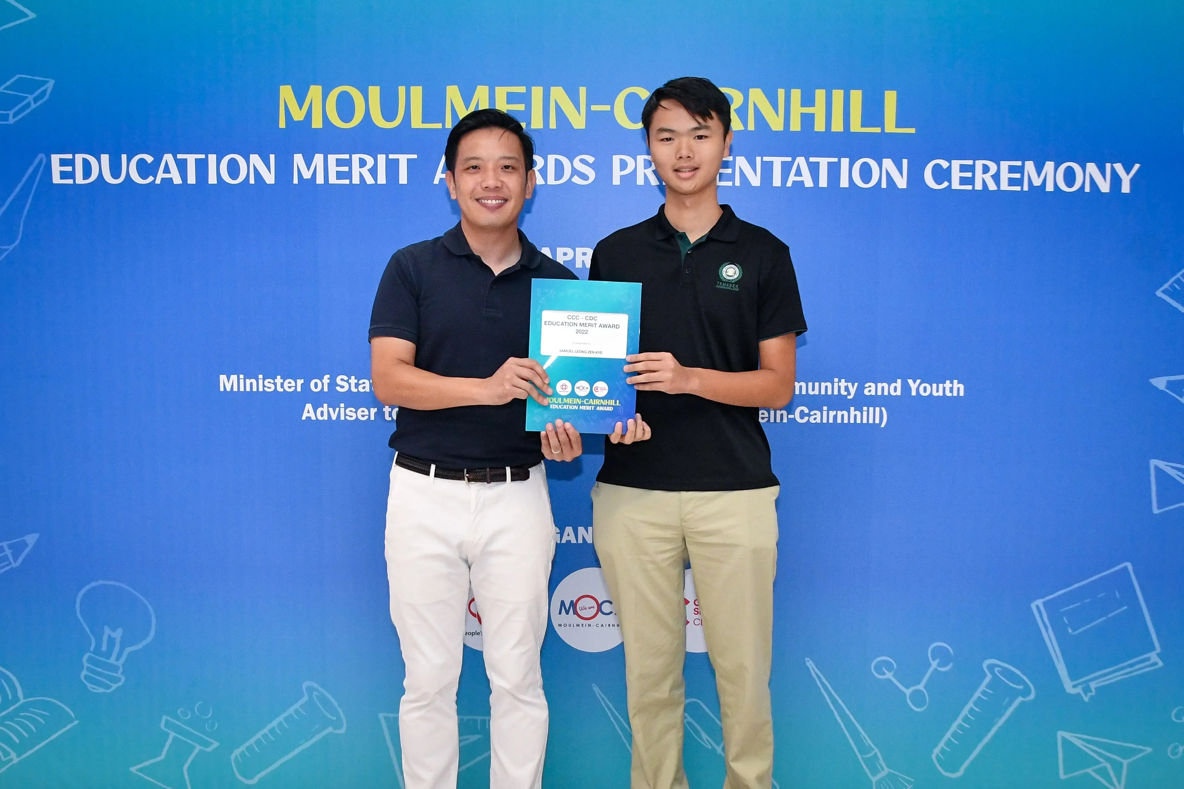 Two men hold a certificate together at the Moulmein-Cairnhill Education Merit Awards Presentation Ceremony.