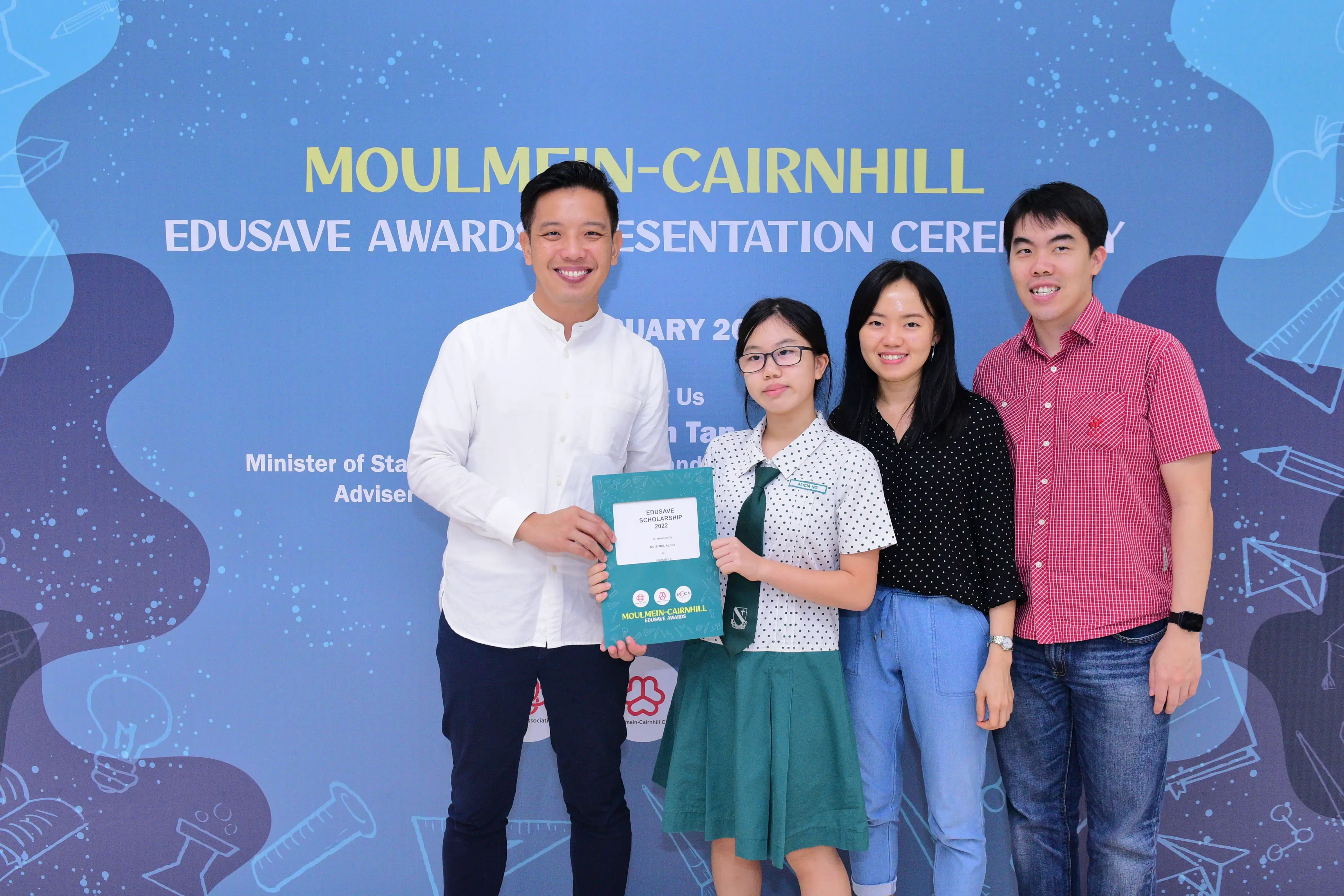 Four people pose together at the Moulmein-Cairnhill Edusave Awards Presentation Ceremony, with a student holding a certificate.