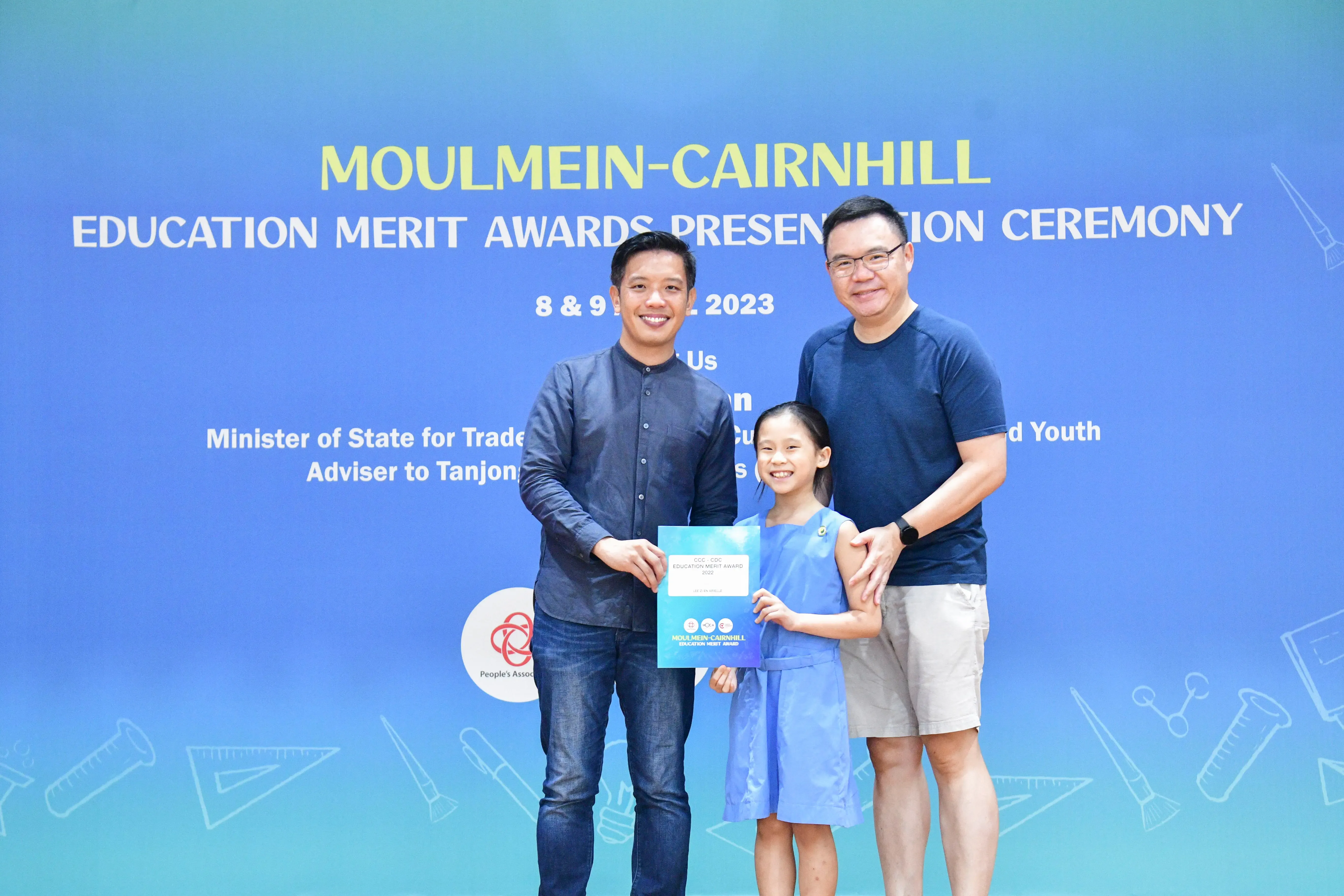 Two men and a young girl smile holding a certificate at the Moulmein-Cairnhill Education Merit Awards 2023.