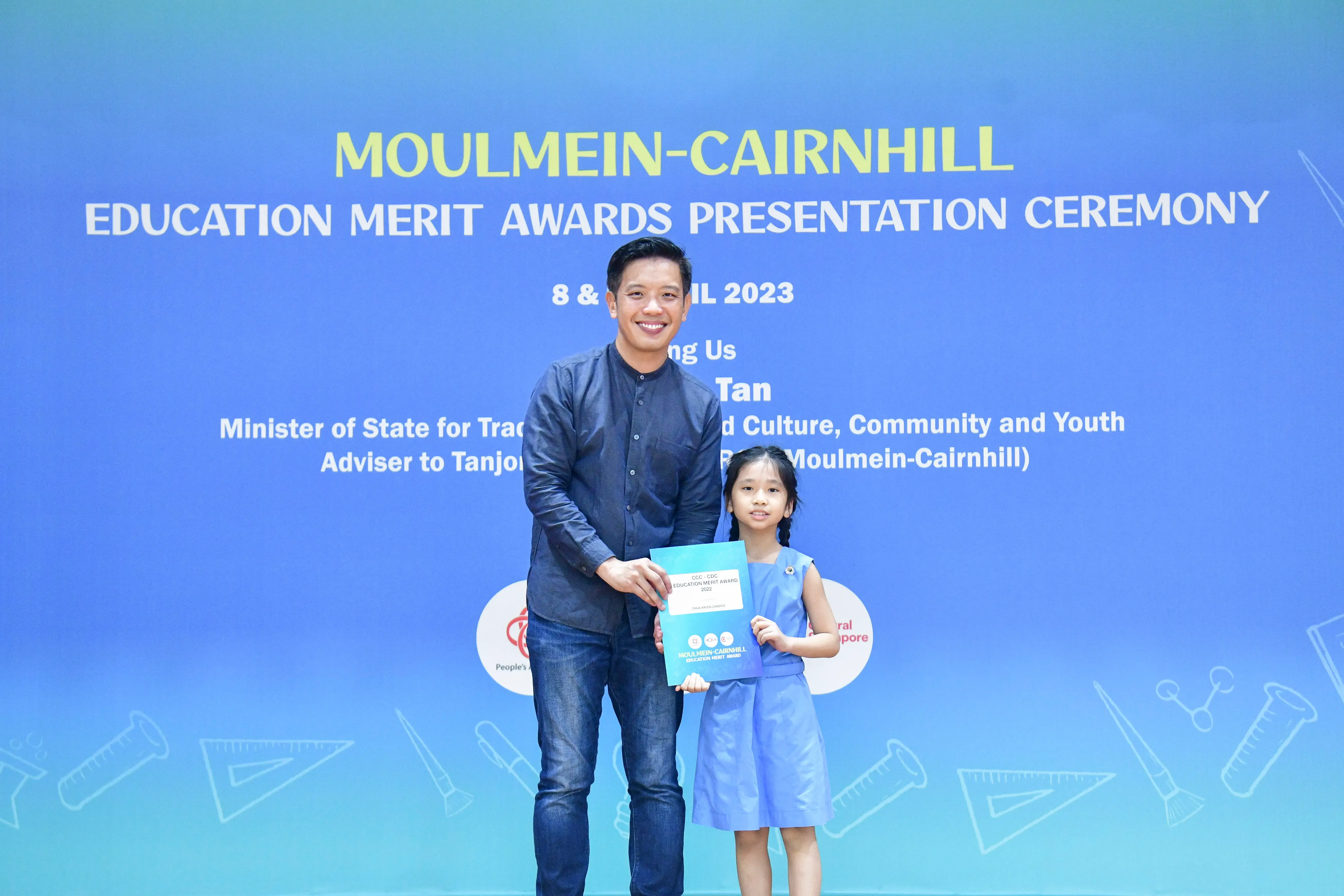 A man and a young girl hold a certificate at the Moulmein-Cairnhill Education Merit Awards Ceremony 2023.