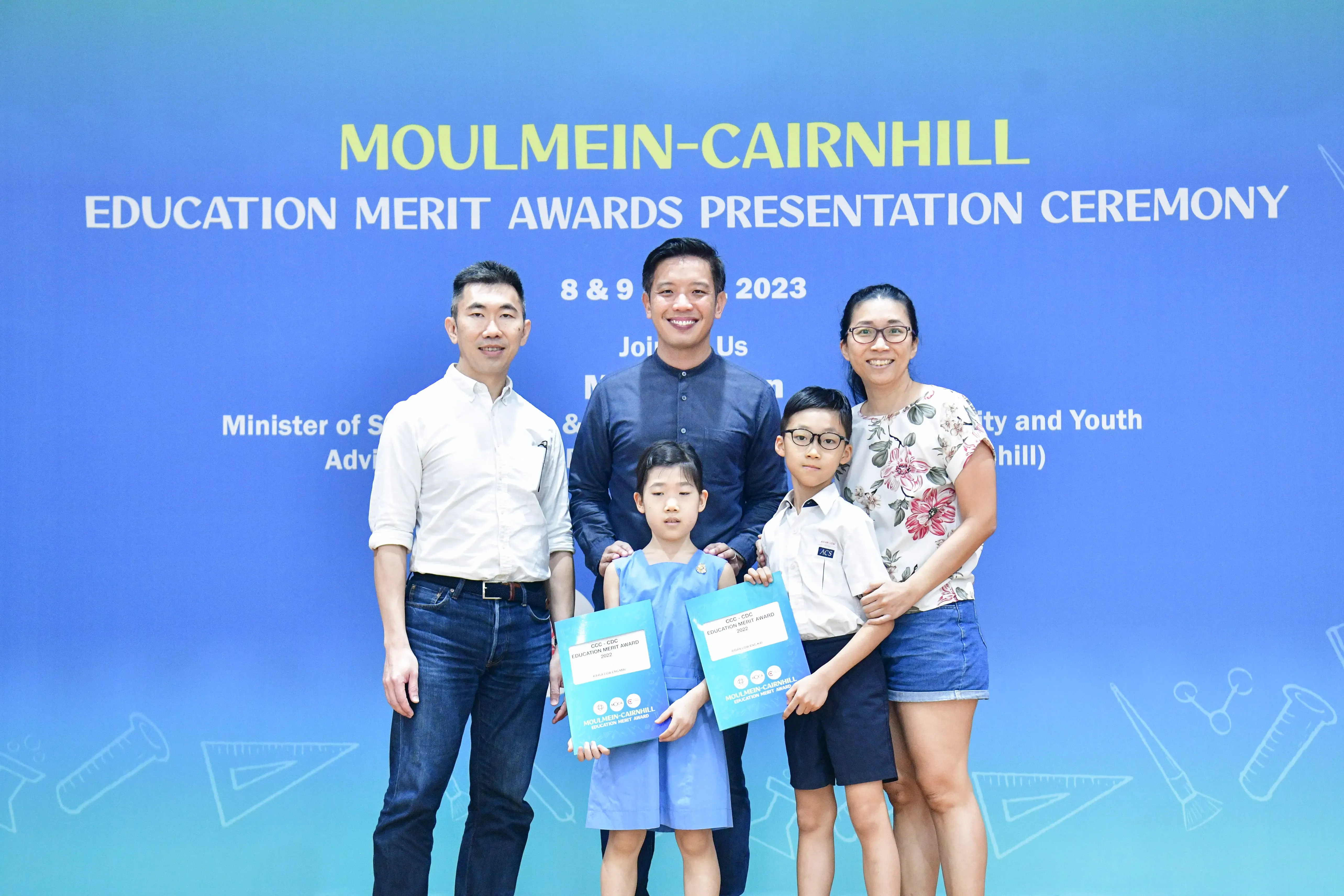 Two adults and two children pose with award certificates at the Moulmein-Cairnhill Education Merit Awards Ceremony 2023.