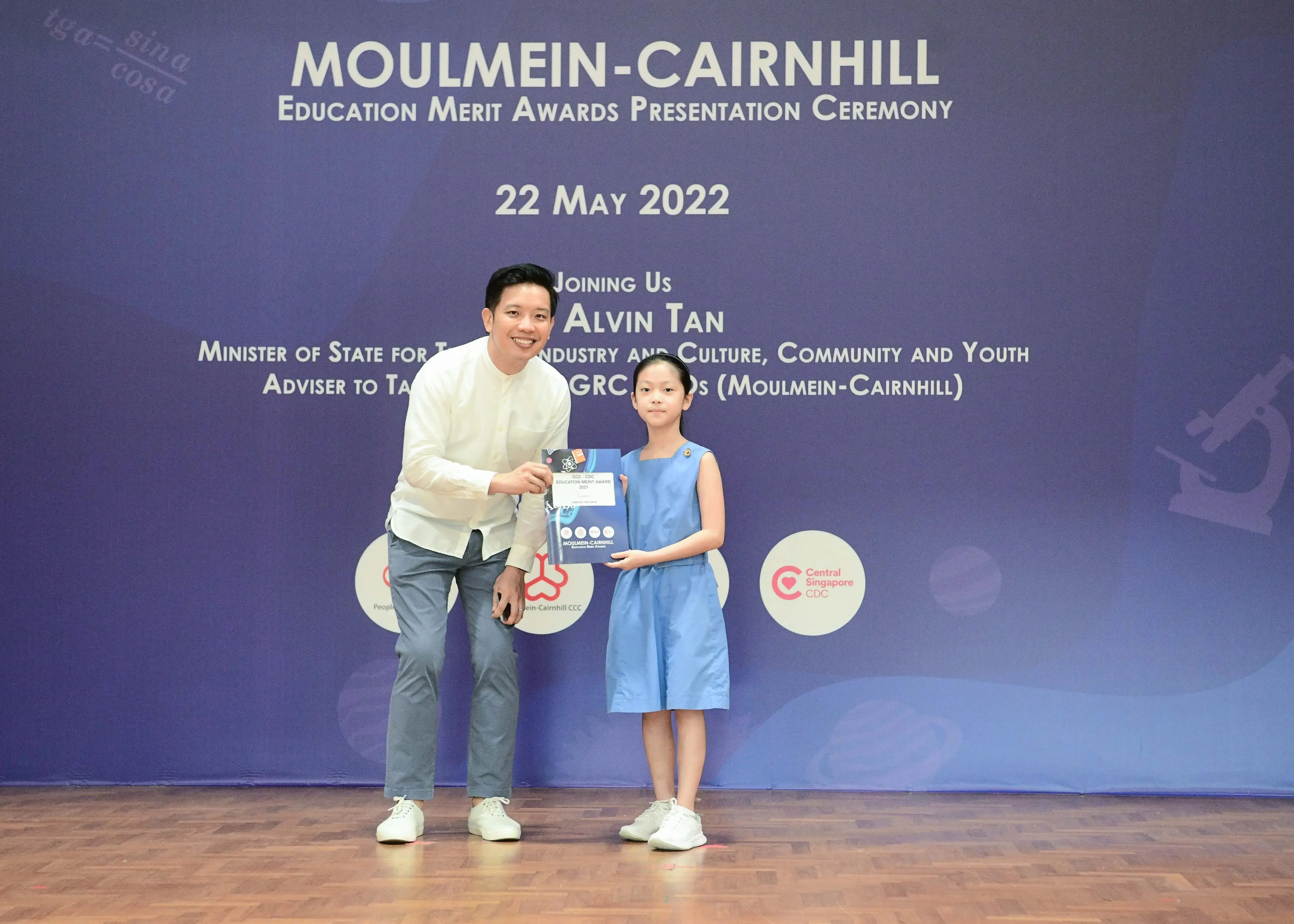 A man and a young girl hold an award together at the Moulmein-Cairnhill Education Merit Awards Ceremony on 22 May 2022.