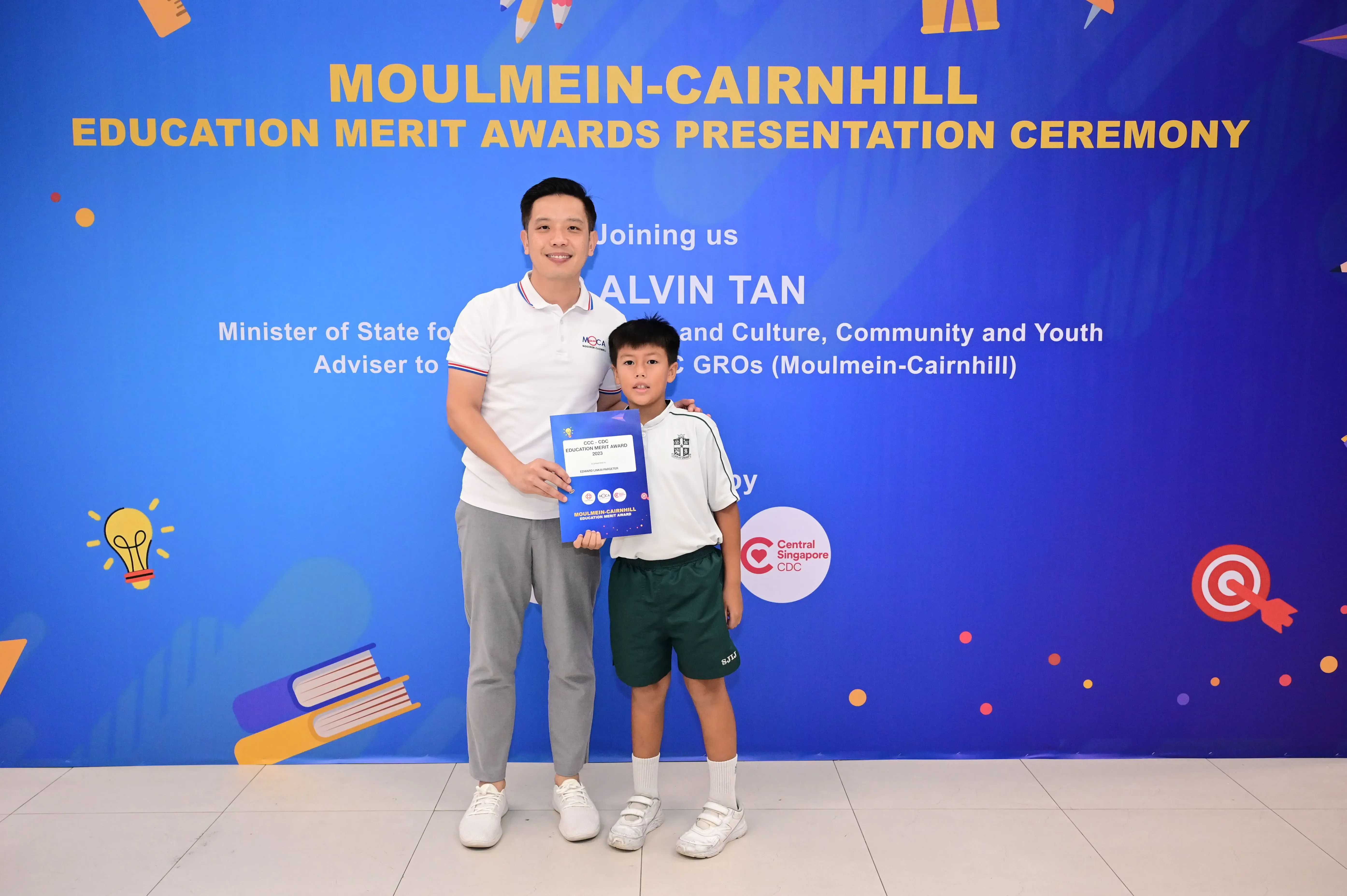 Man and young boy holding an award certificate at Moulmein-Cairnhill Education Merit Awards Presentation Ceremony.