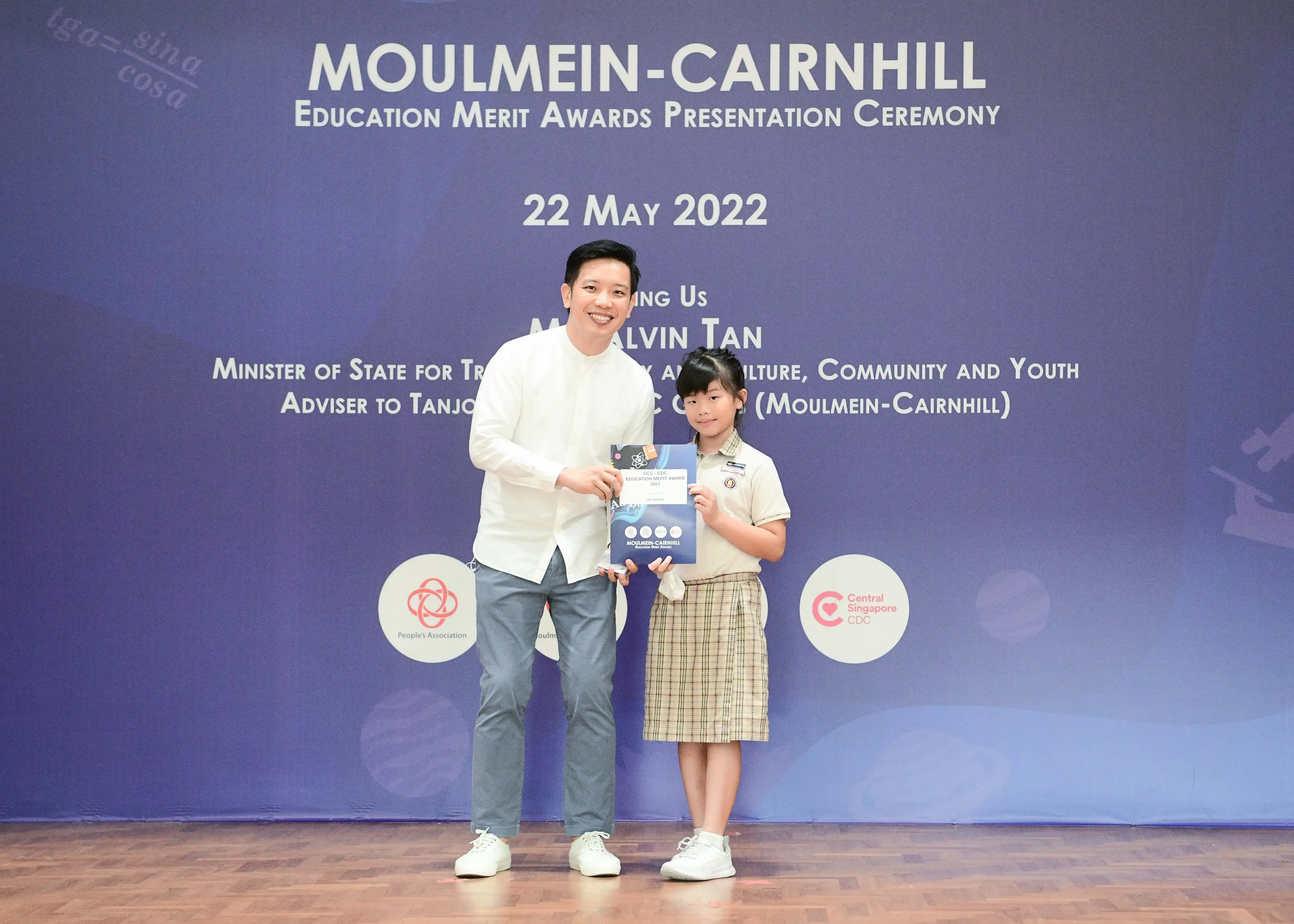 A man and a young girl in school uniform hold an award certificate at the Moulmein-Cairnhill Education Merit Awards on 22 May 2022.