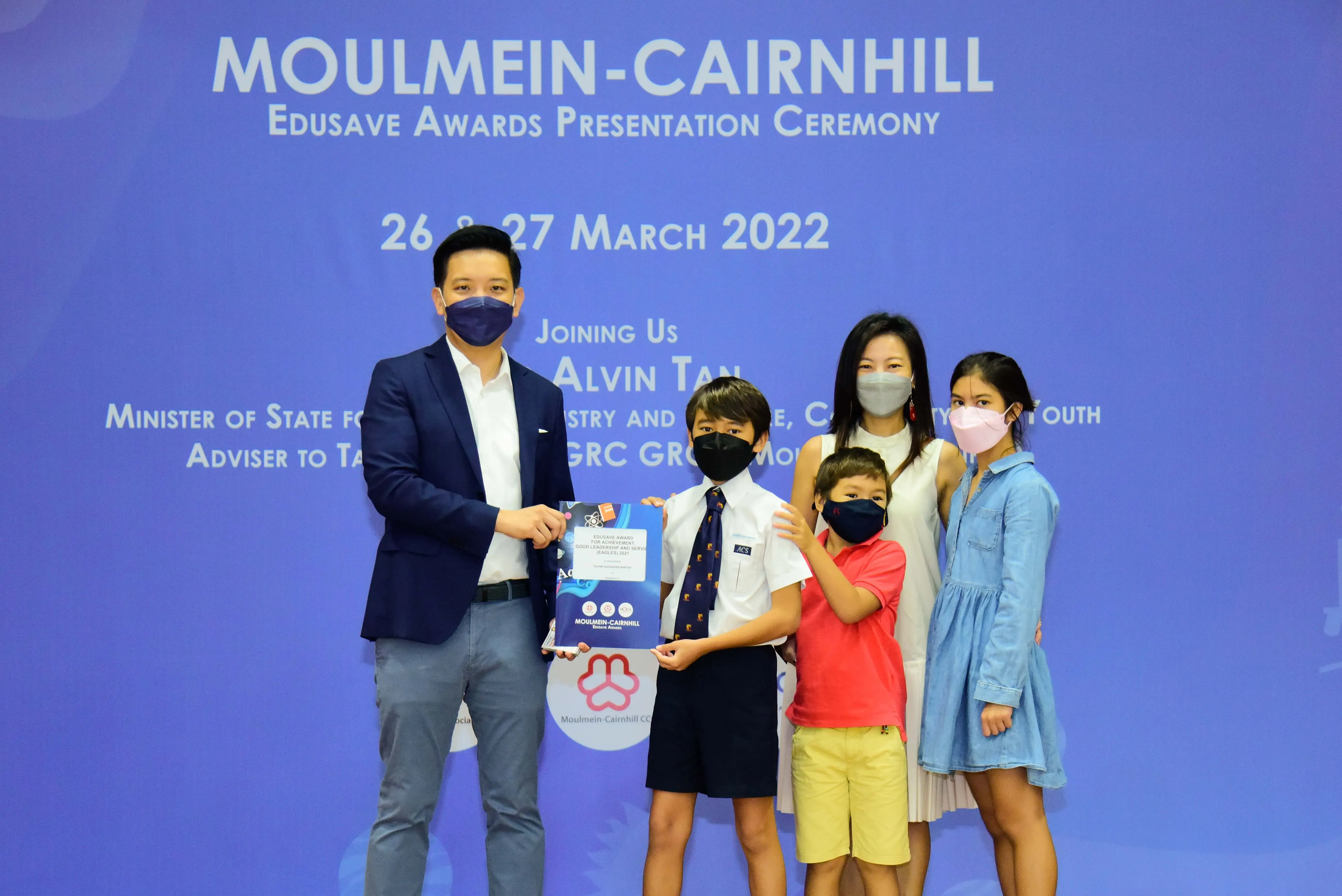 Five masked people pose at the Moulmein-Cairnhill Edusave Awards Presentation Ceremony on 26-27 March 2022.