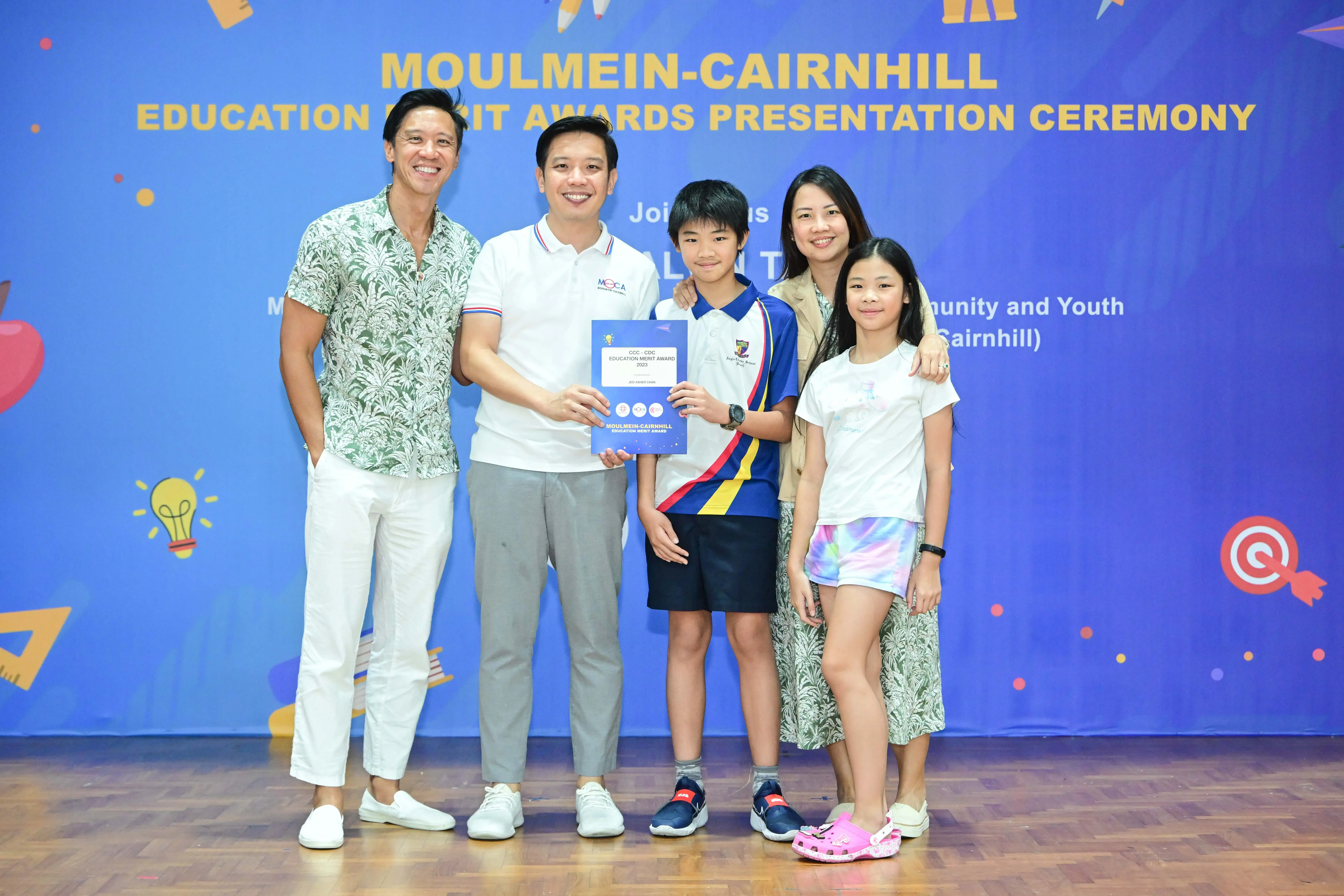 Five people pose with a merit award certificate at the Moulmein-Cairnhill Education Merit Awards Presentation Ceremony.