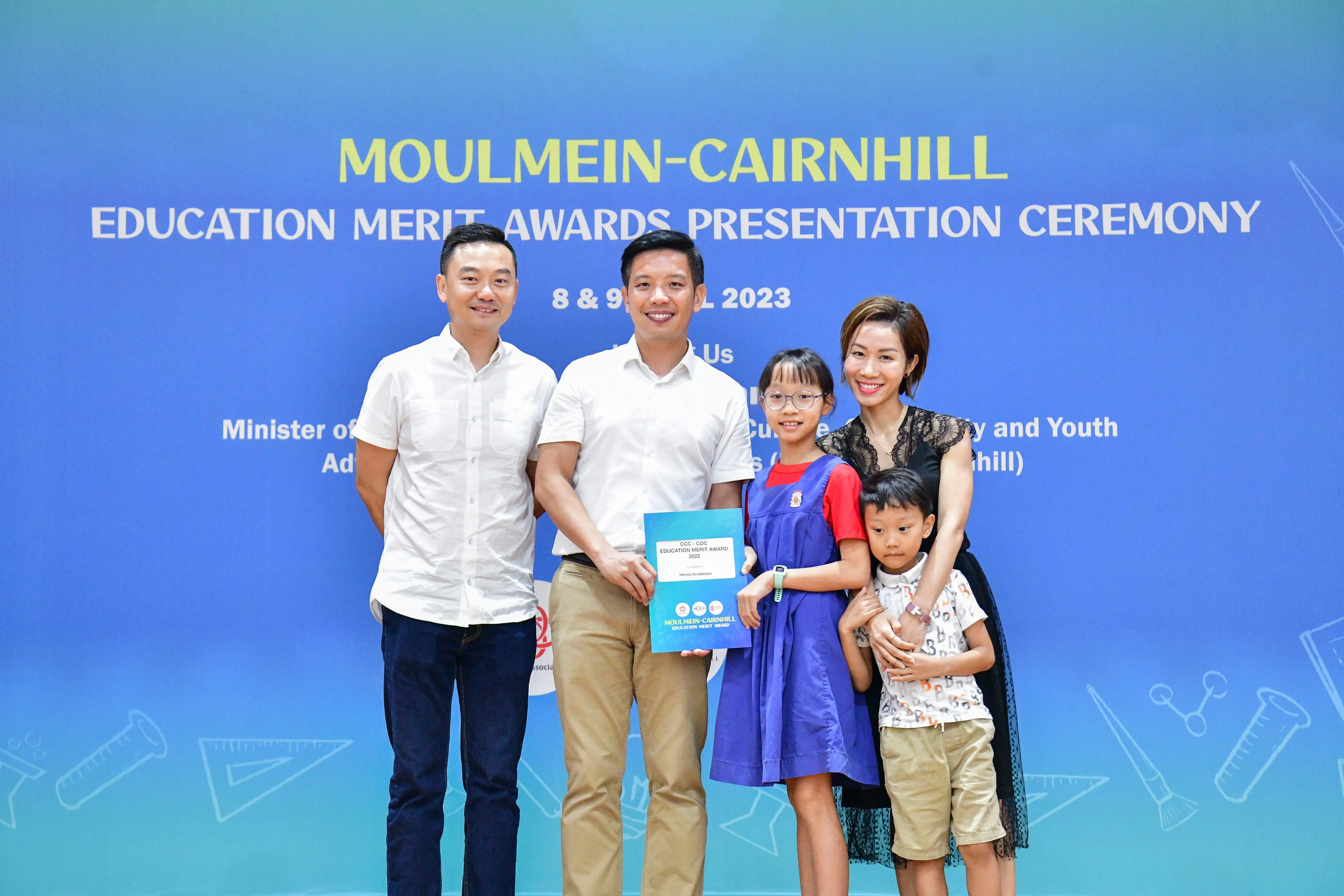 Five people pose with an award certificate at the Moulmein-Cairnhill Education Merit Awards Ceremony 2023.