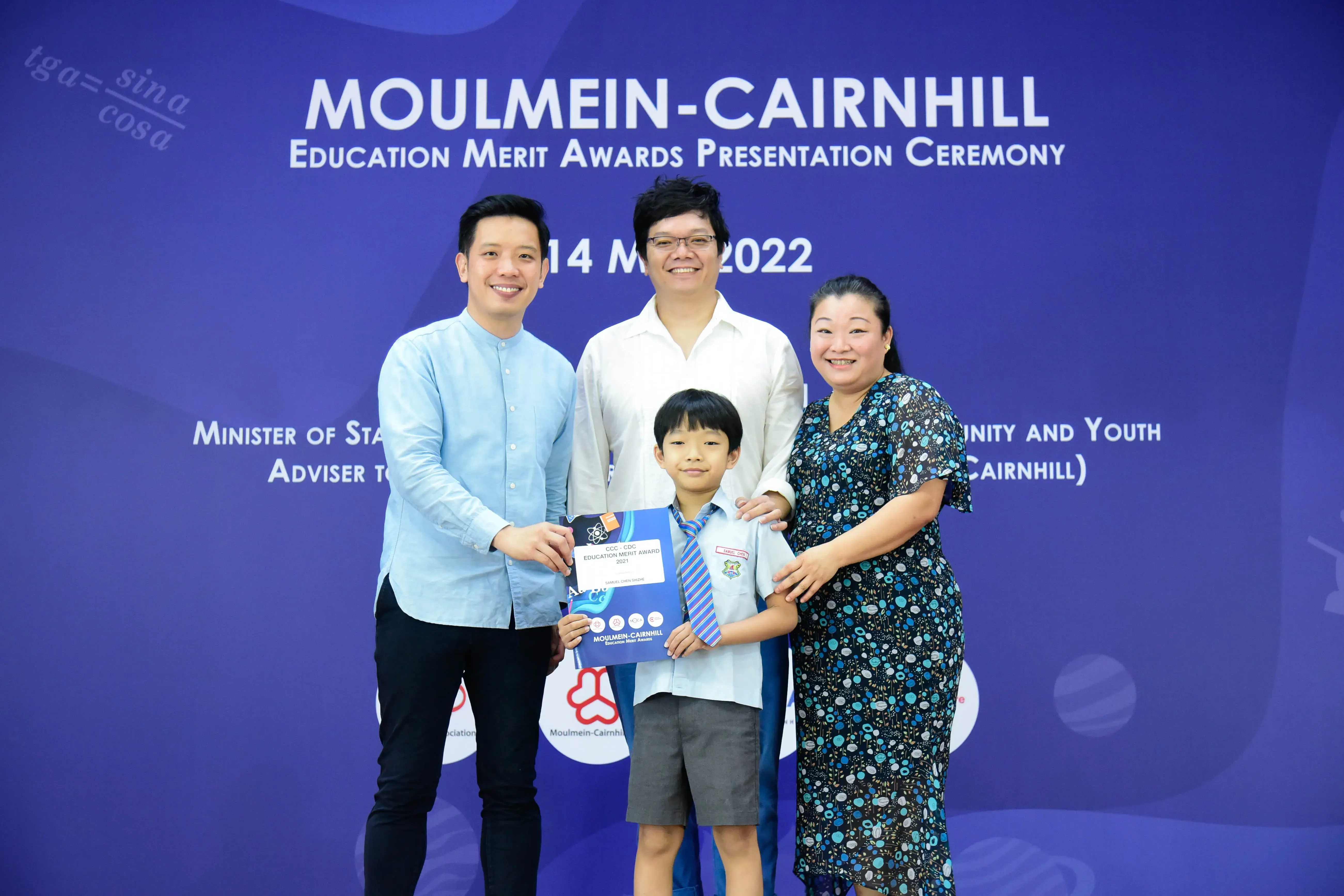 Three adults and a boy holding an award certificate at the Moulmein-Cairnhill Education Merit Awards Ceremony 2022.