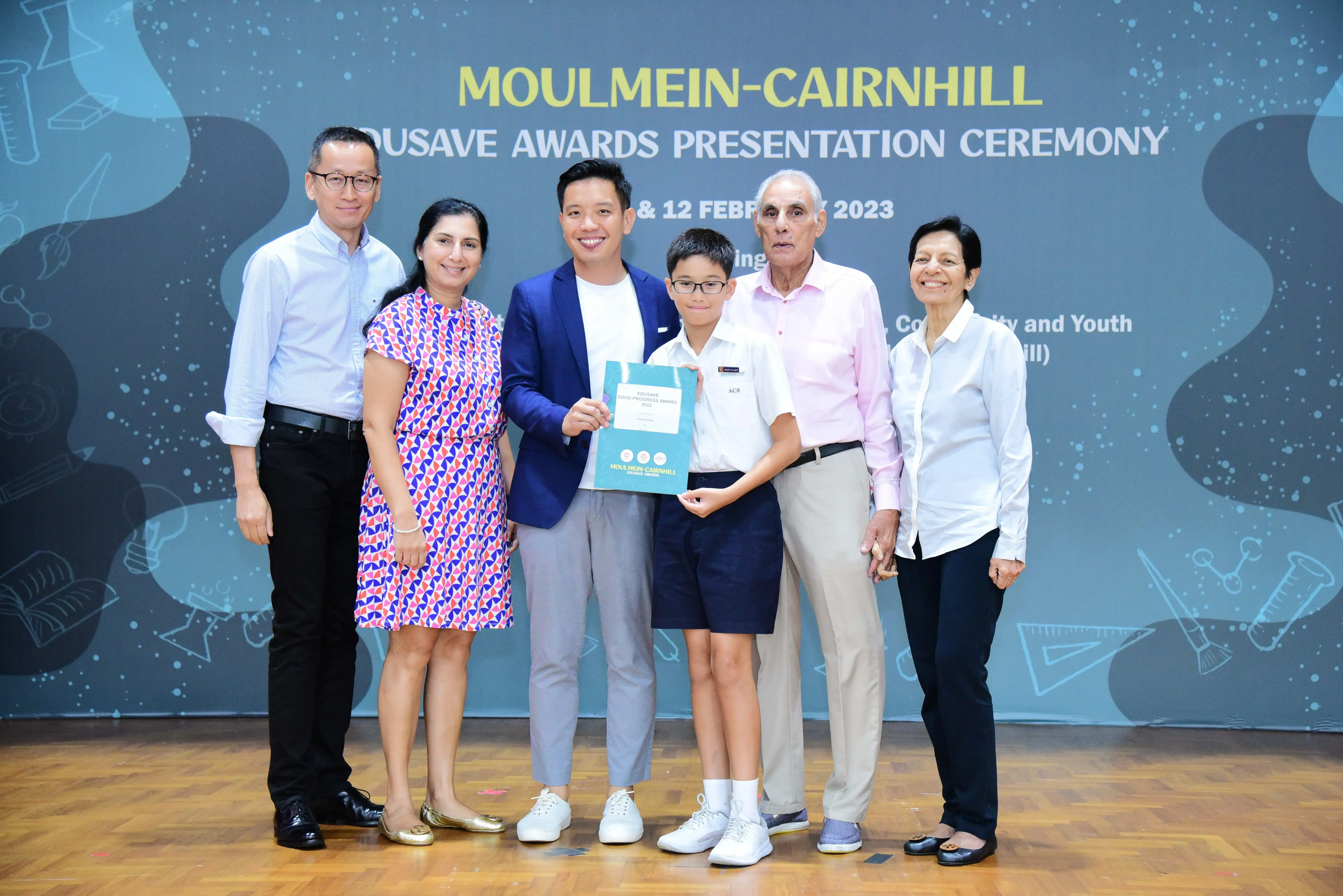 Six people pose on a stage at the Moulmein-Cairnhill Edusave Awards Presentation Ceremony in February 2023.