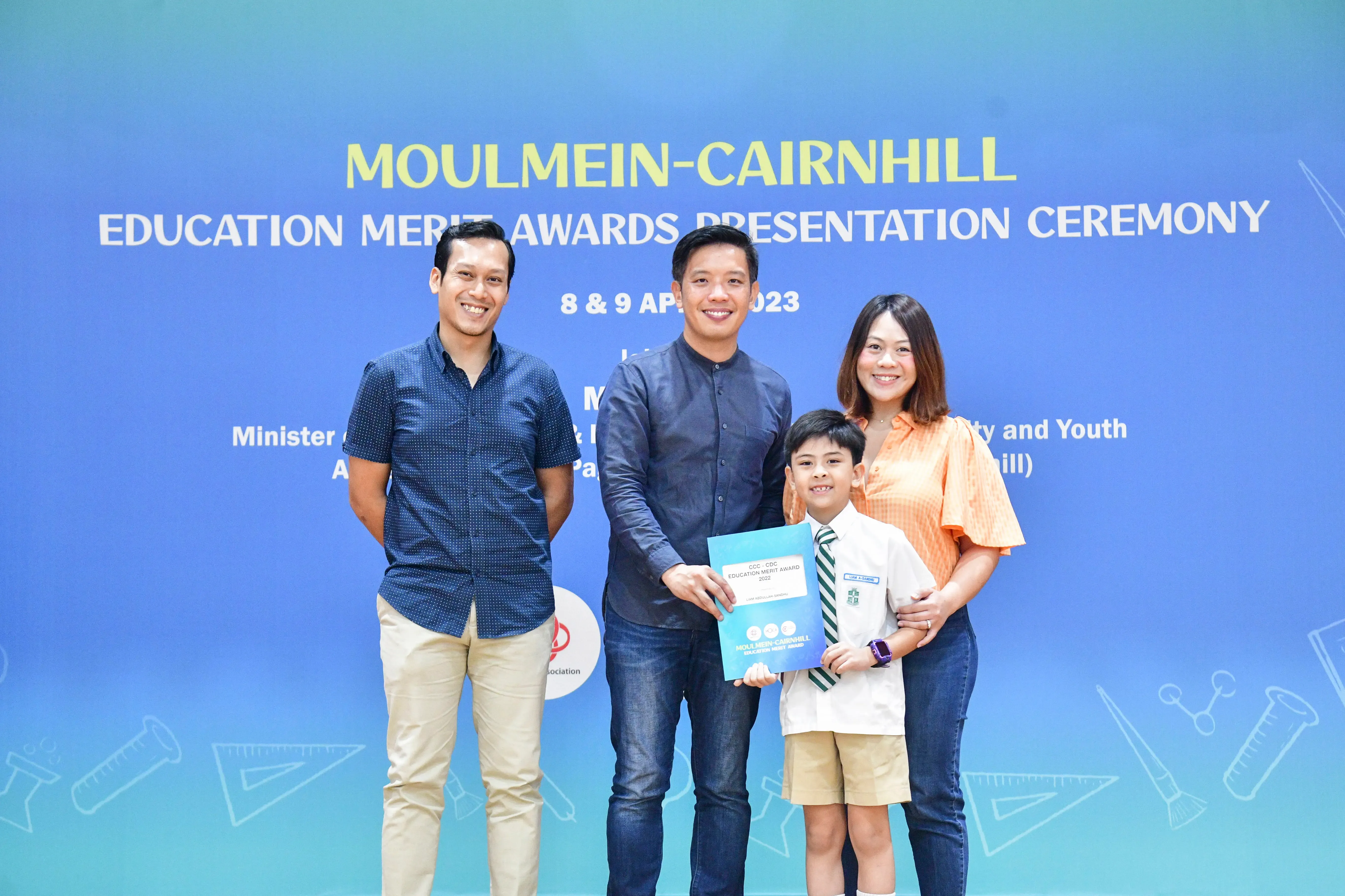 Three adults and a young boy pose with an award certificate at the Moulmein-Cairnhill Education Merit Awards 2023.