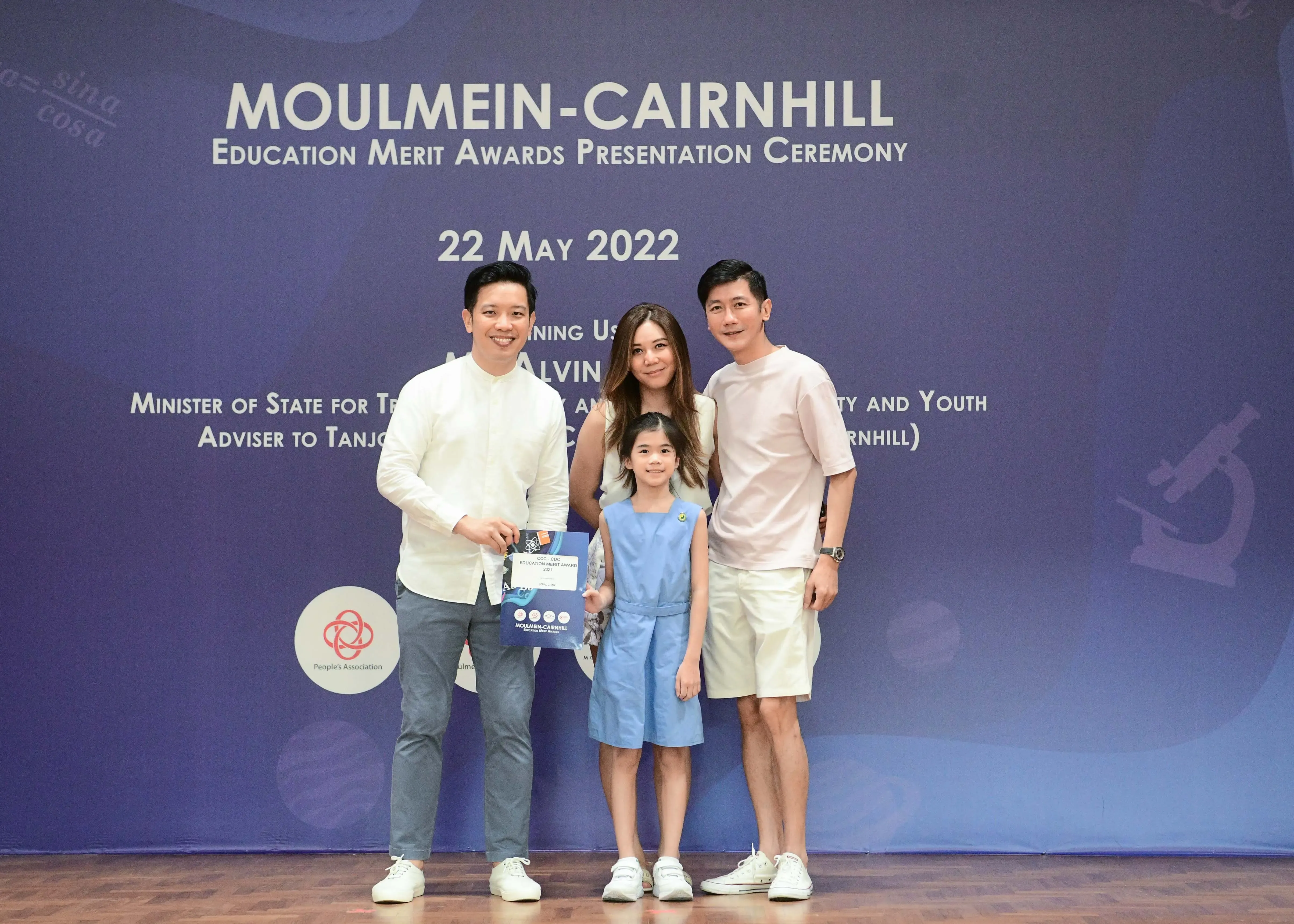 Three adults and a young girl pose with an award at the Moulmein-Cairnhill Education Merit Awards Ceremony, 22 May 2022.