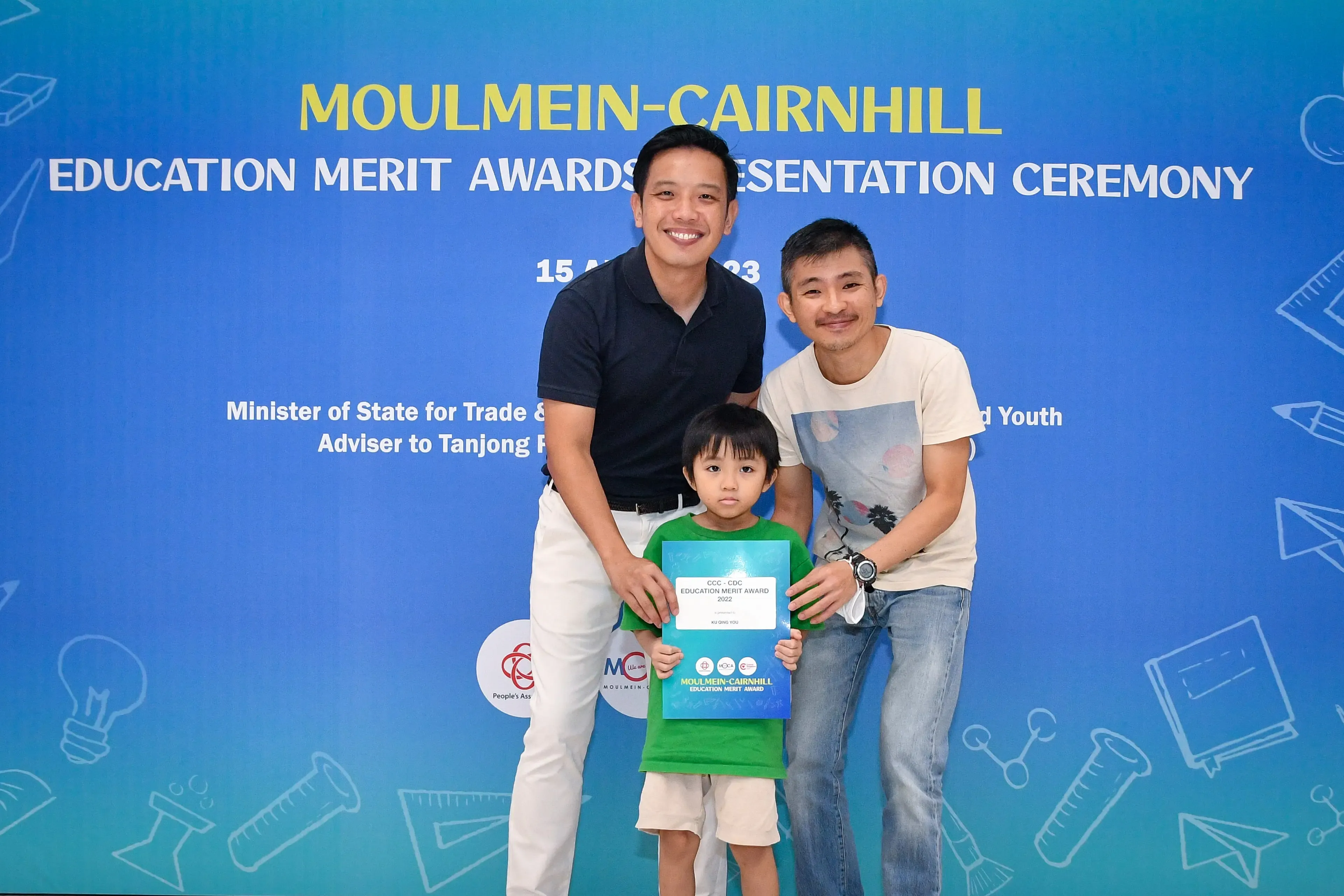 Two men and a young boy holding a certificate pose at the Moulmein-Cairnhill Education Merit Awards Ceremony.