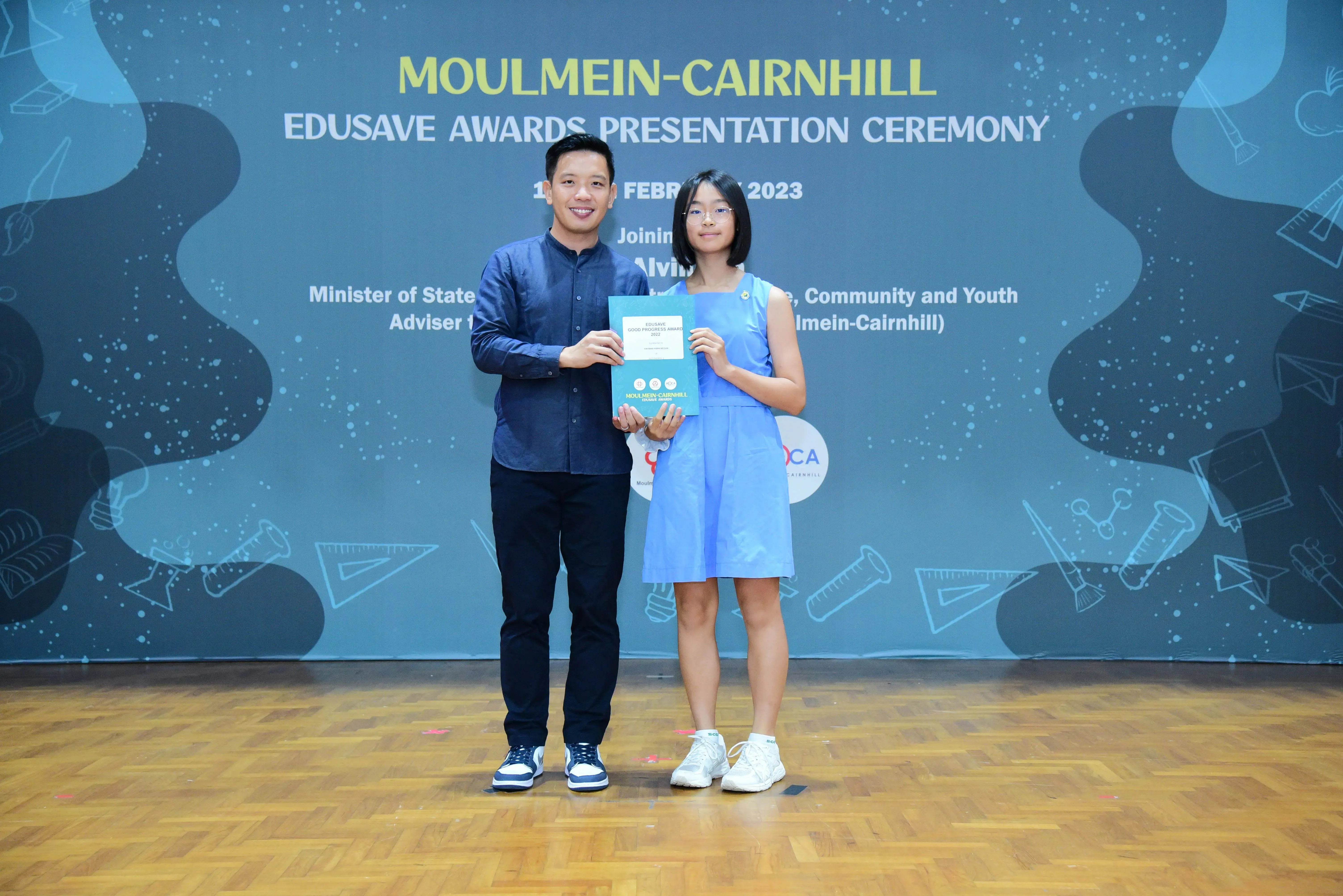 A man and a young girl hold a certificate together at the Moulmein-Cairnhill Edusave Awards Presentation Ceremony 2023.