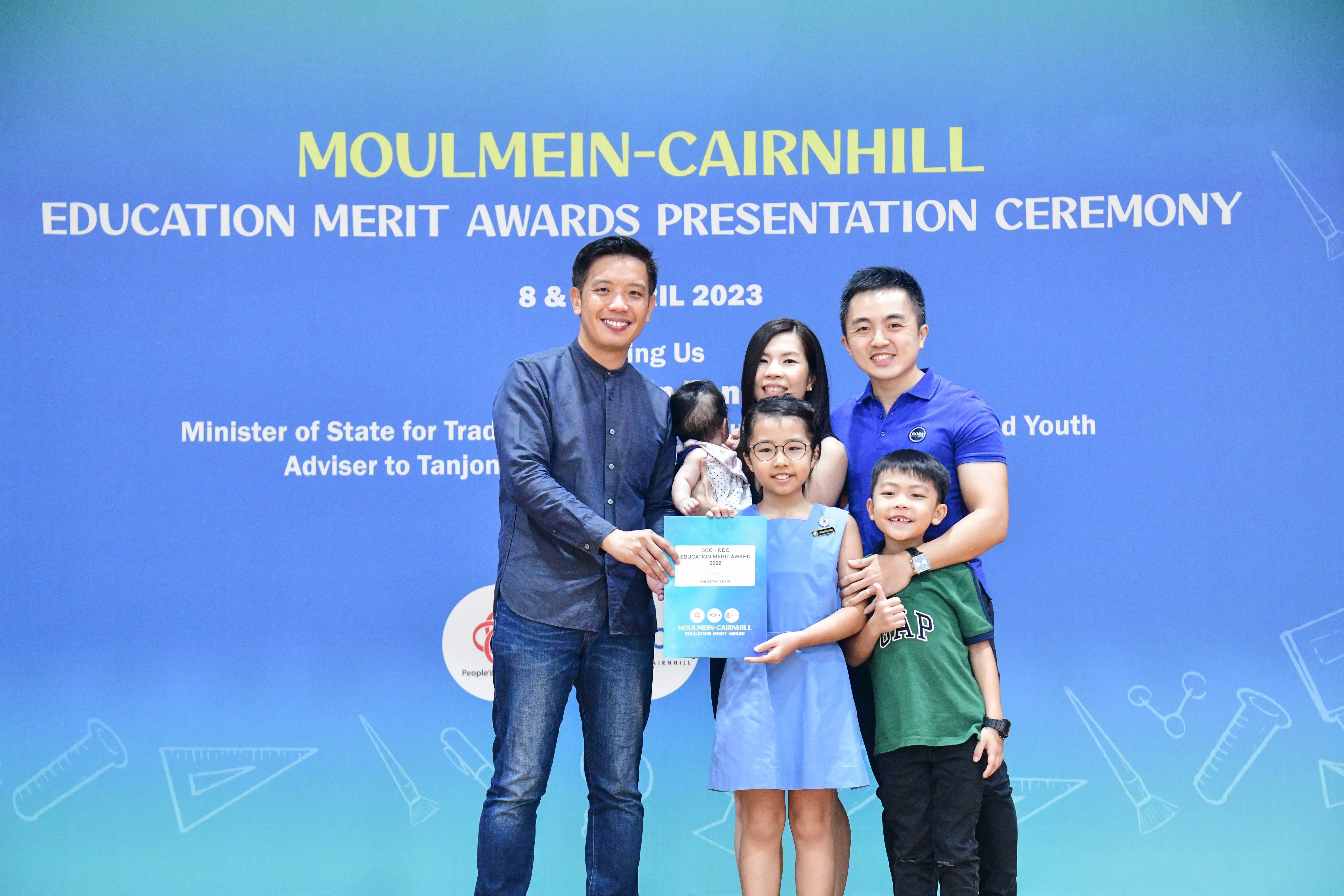A family with two adults and three children pose with an award at the Moulmein-Cairnhill Education Merit Awards 2023.