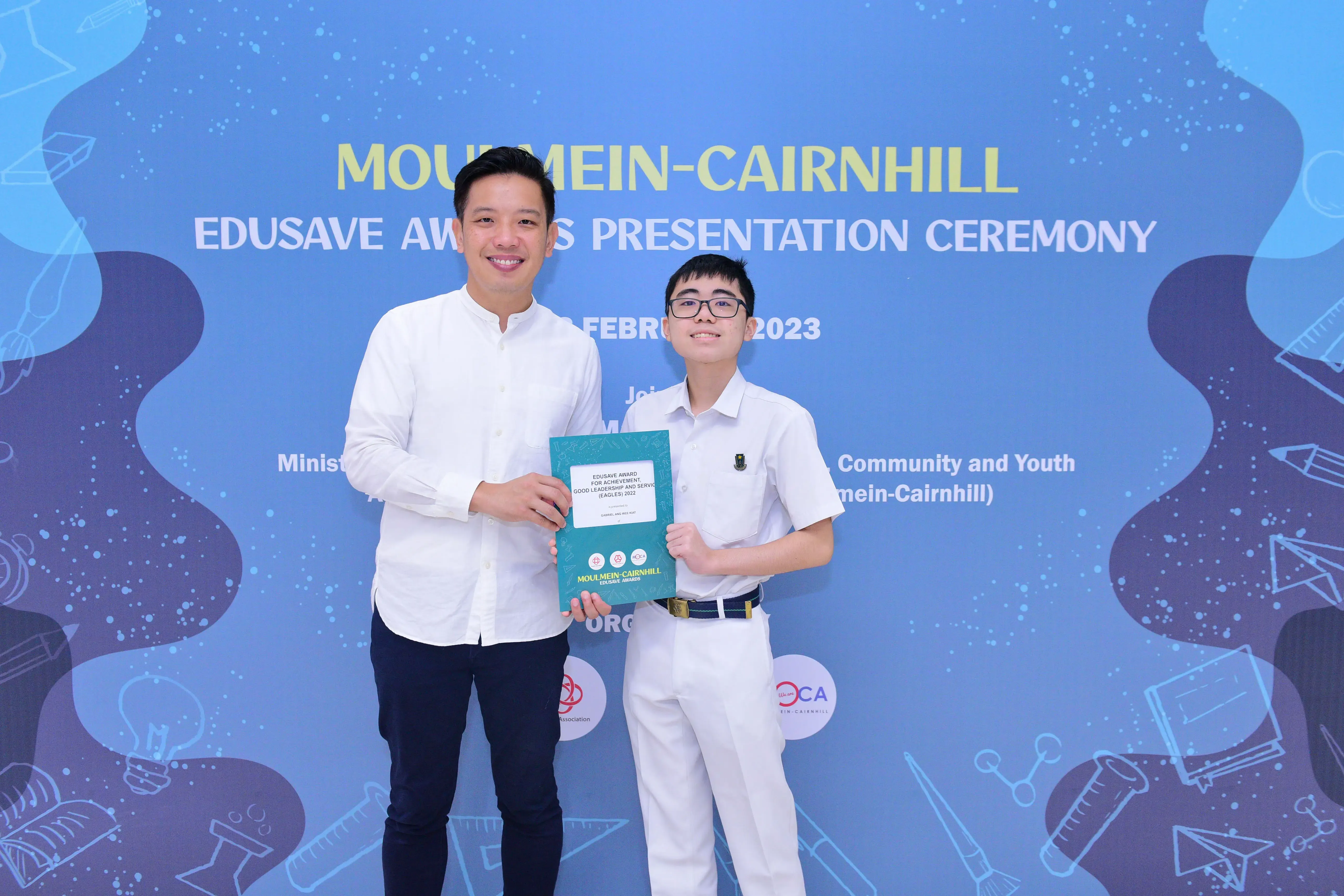 Two people smile holding a certificate at the Moulmein-Cairnhill Edusave Awards Presentation Ceremony 2023.