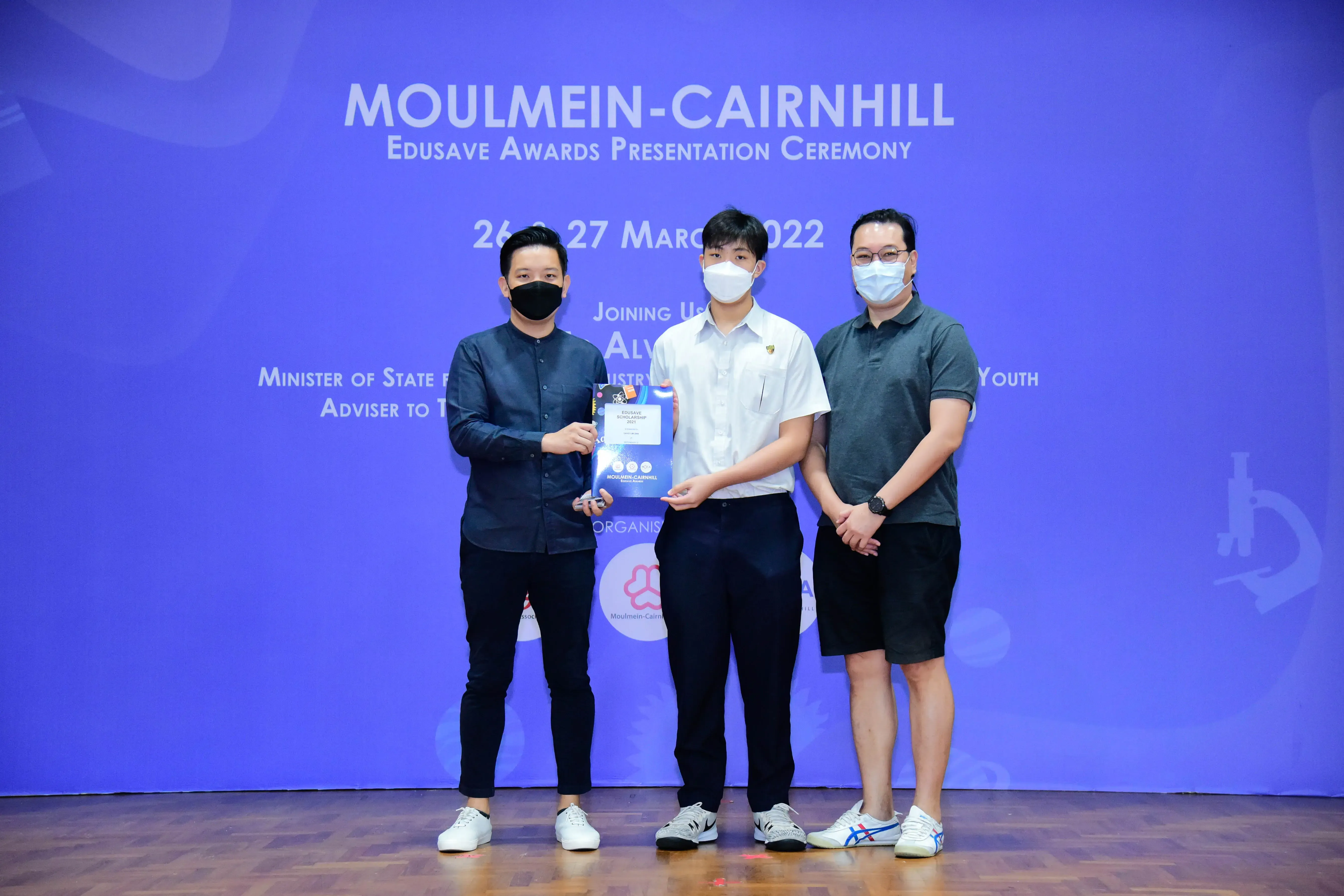 Three masked people pose at the Moulmein-Cairnhill Edusave Awards Presentation Ceremony on 26-27 March 2022.