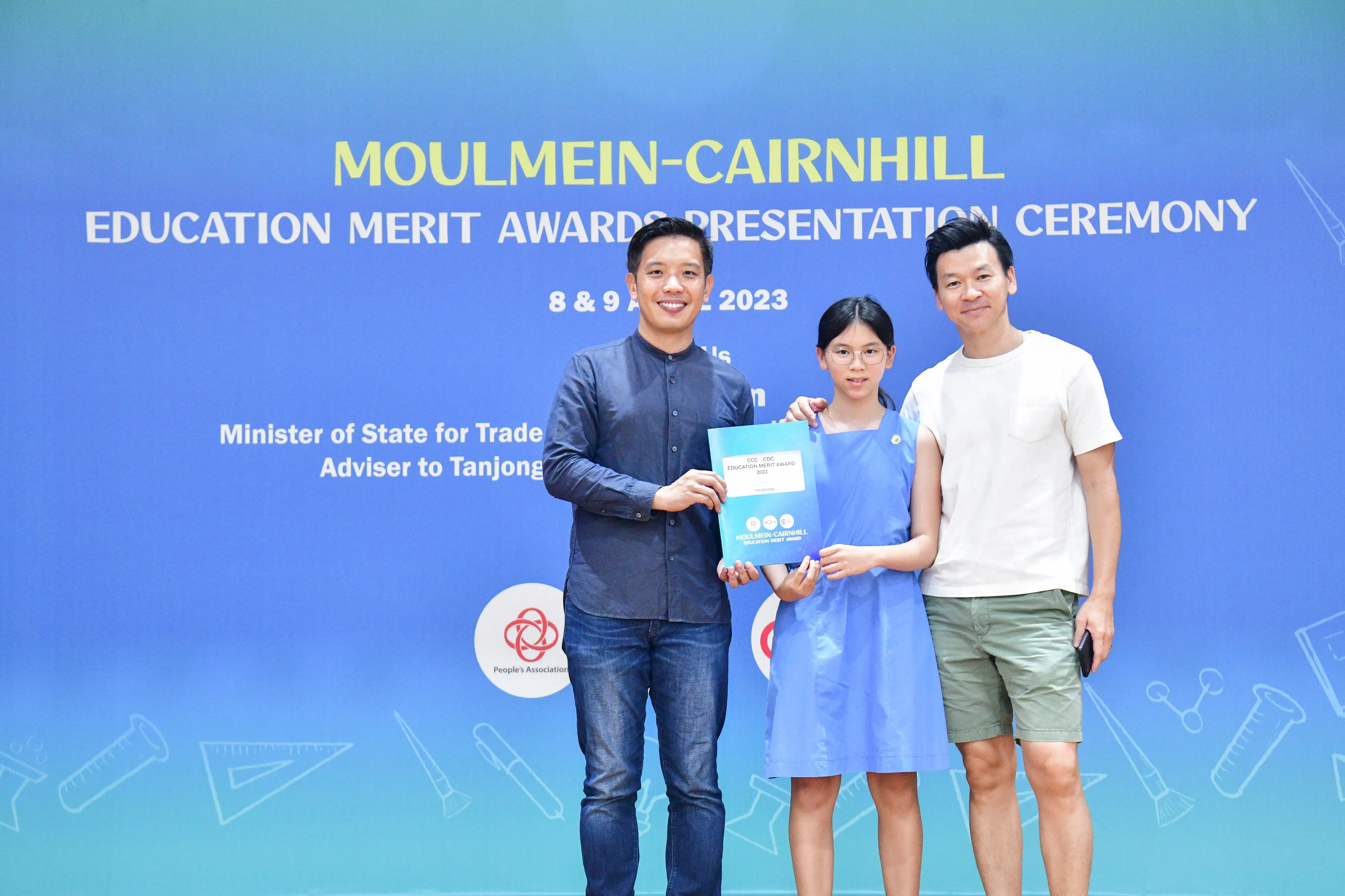 Two men and a young girl pose at the Moulmein-Cairnhill Education Merit Awards Presentation Ceremony 2023.