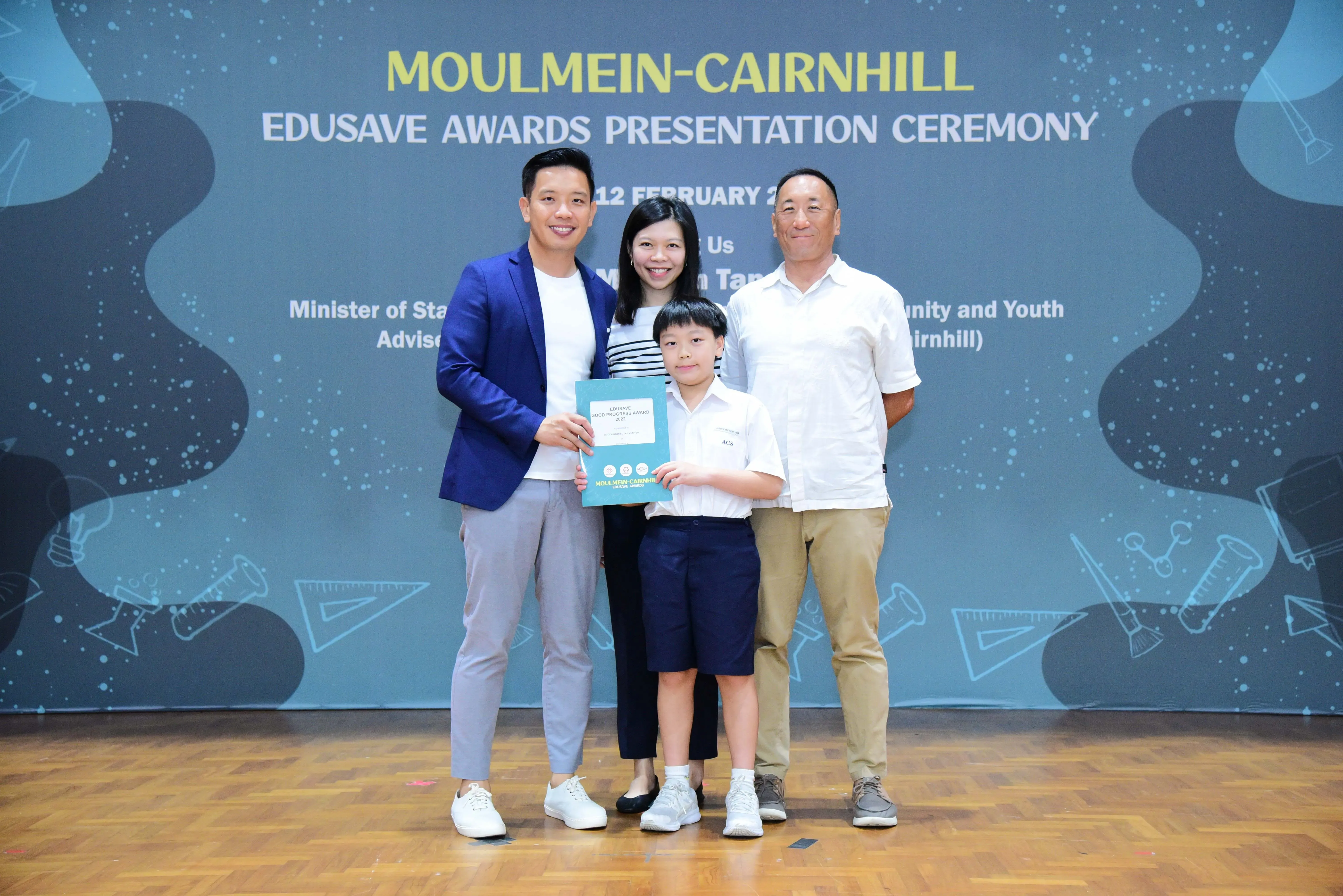 Three adults and a boy holding a certificate pose at the Moulmein-Cairnhill Edusave Awards Presentation Ceremony.
