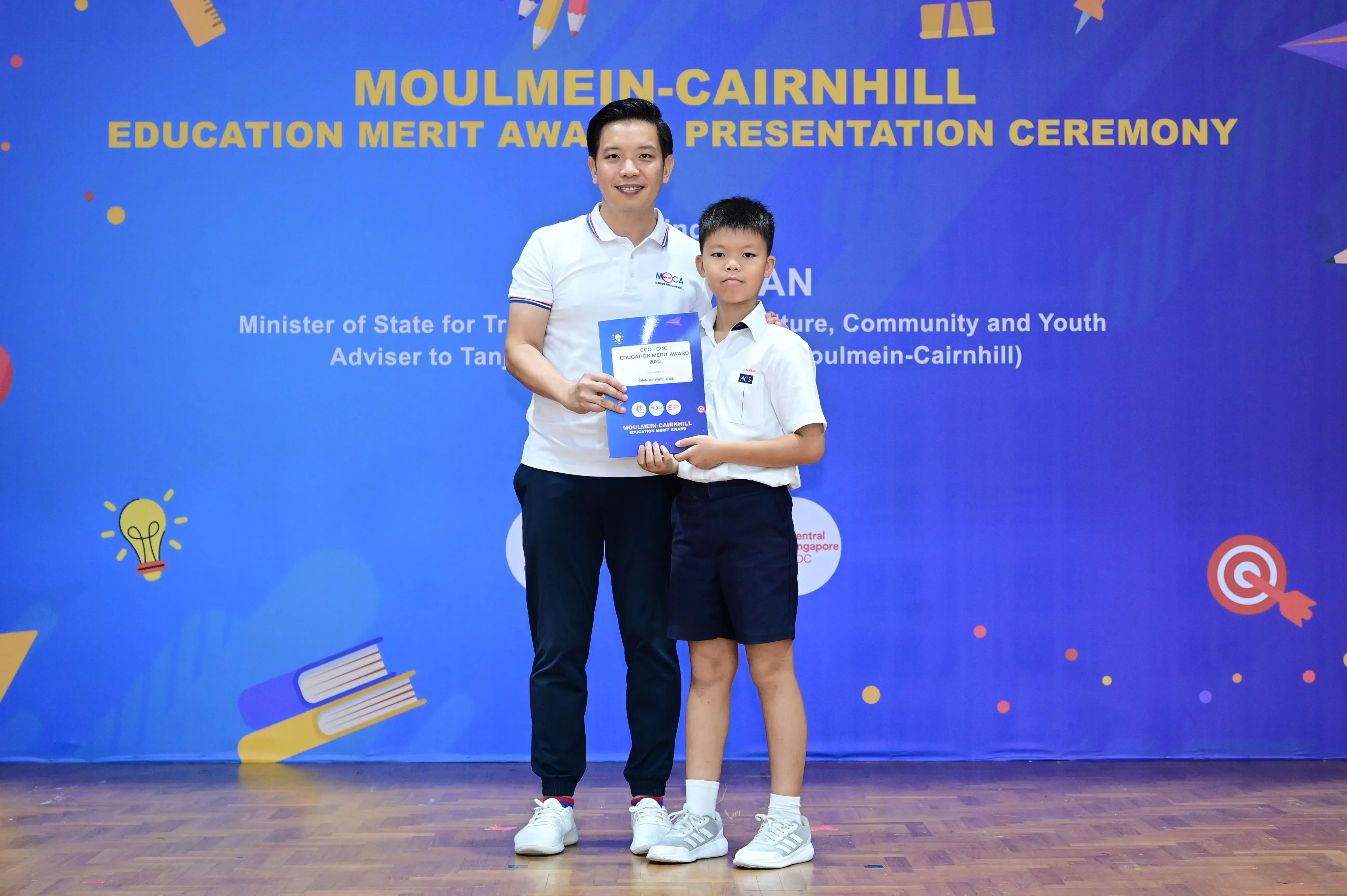 Man and young boy holding an award certificate at Moulmein-Cairnhill Education Merit Award Presentation Ceremony.