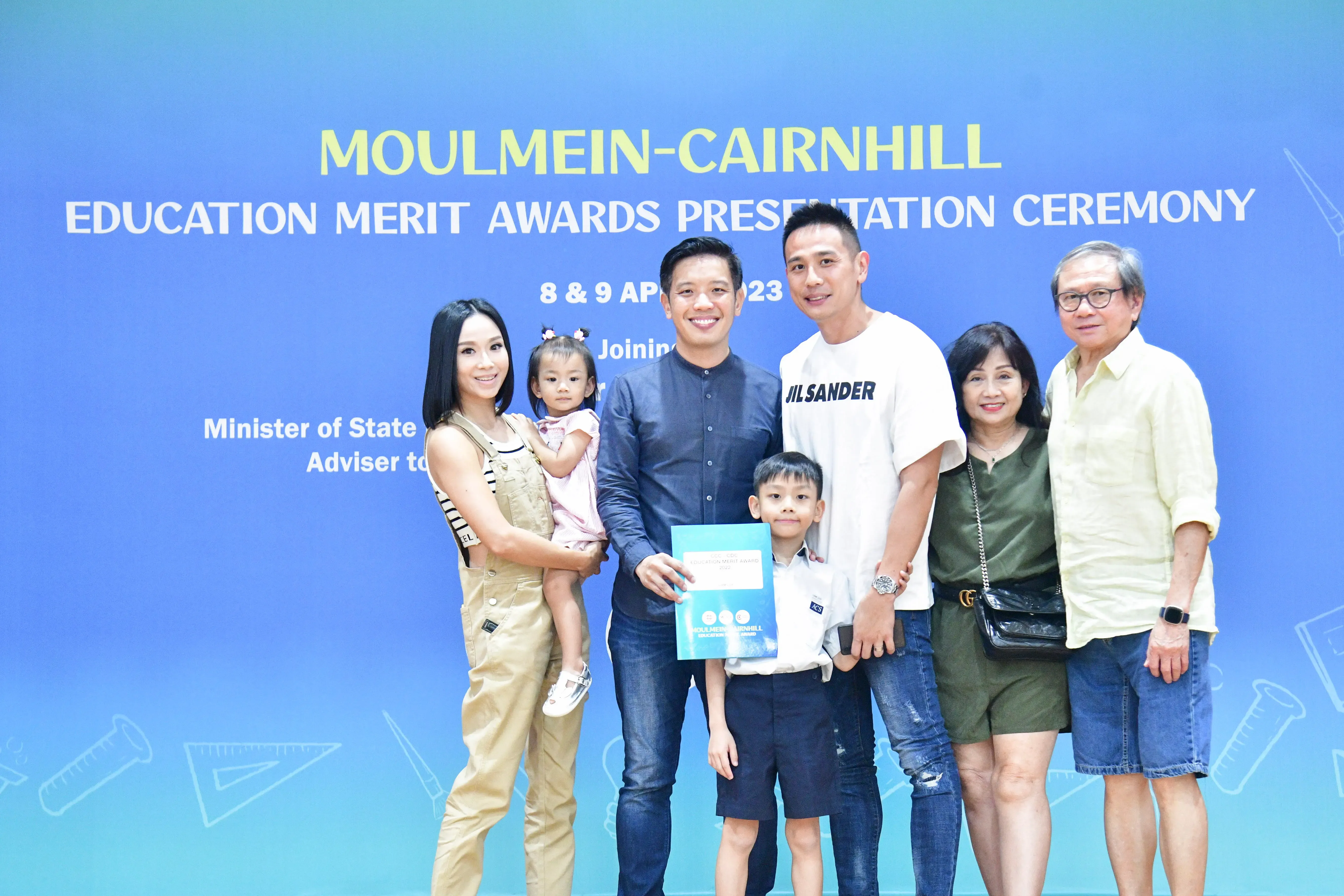 Six adults and two children pose at the Moulmein-Cairnhill Education Merit Awards Presentation Ceremony in 2023.
