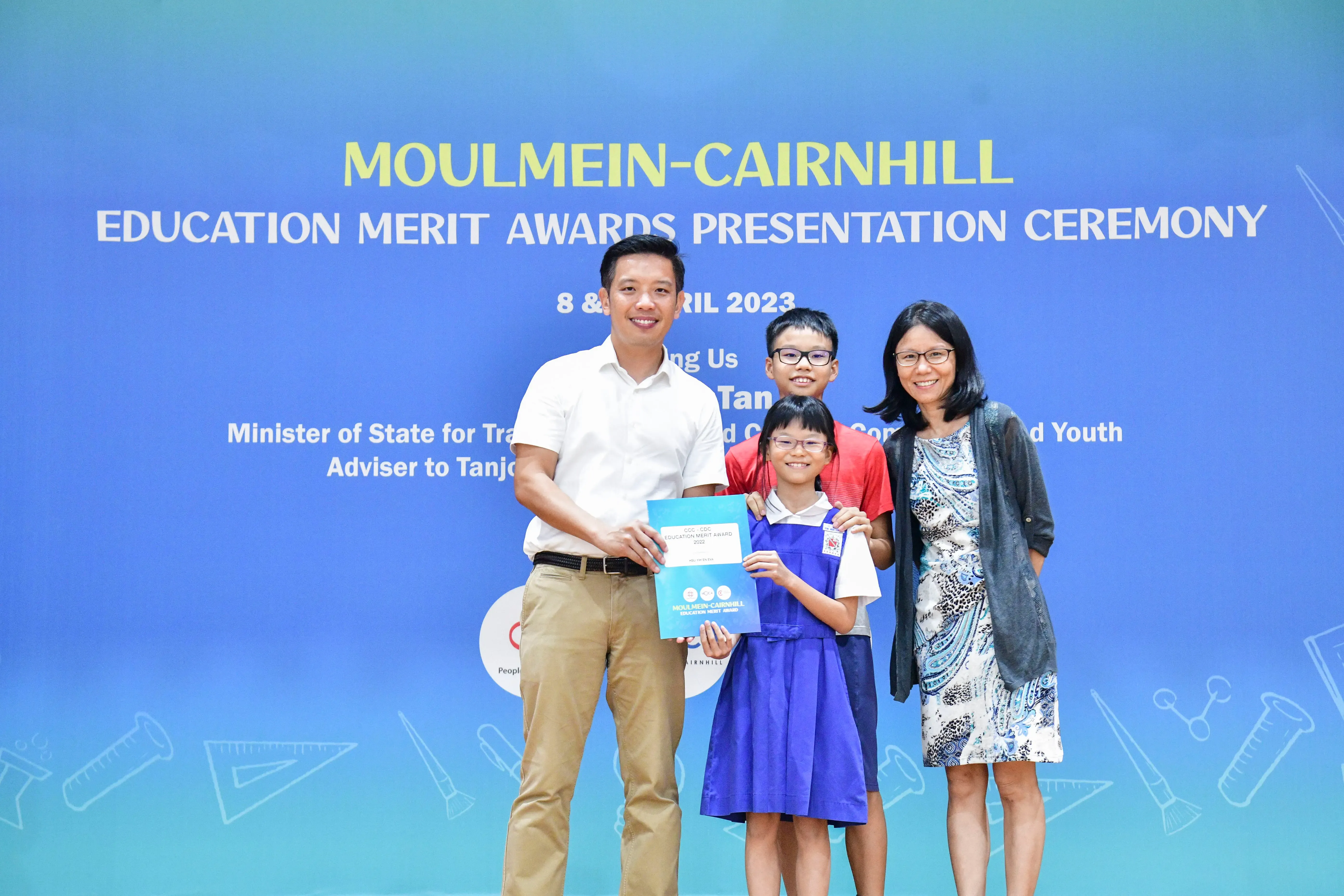 Two adults and two children pose with award certificates at the Moulmein-Cairnhill Education Merit Awards Ceremony, April 2023.