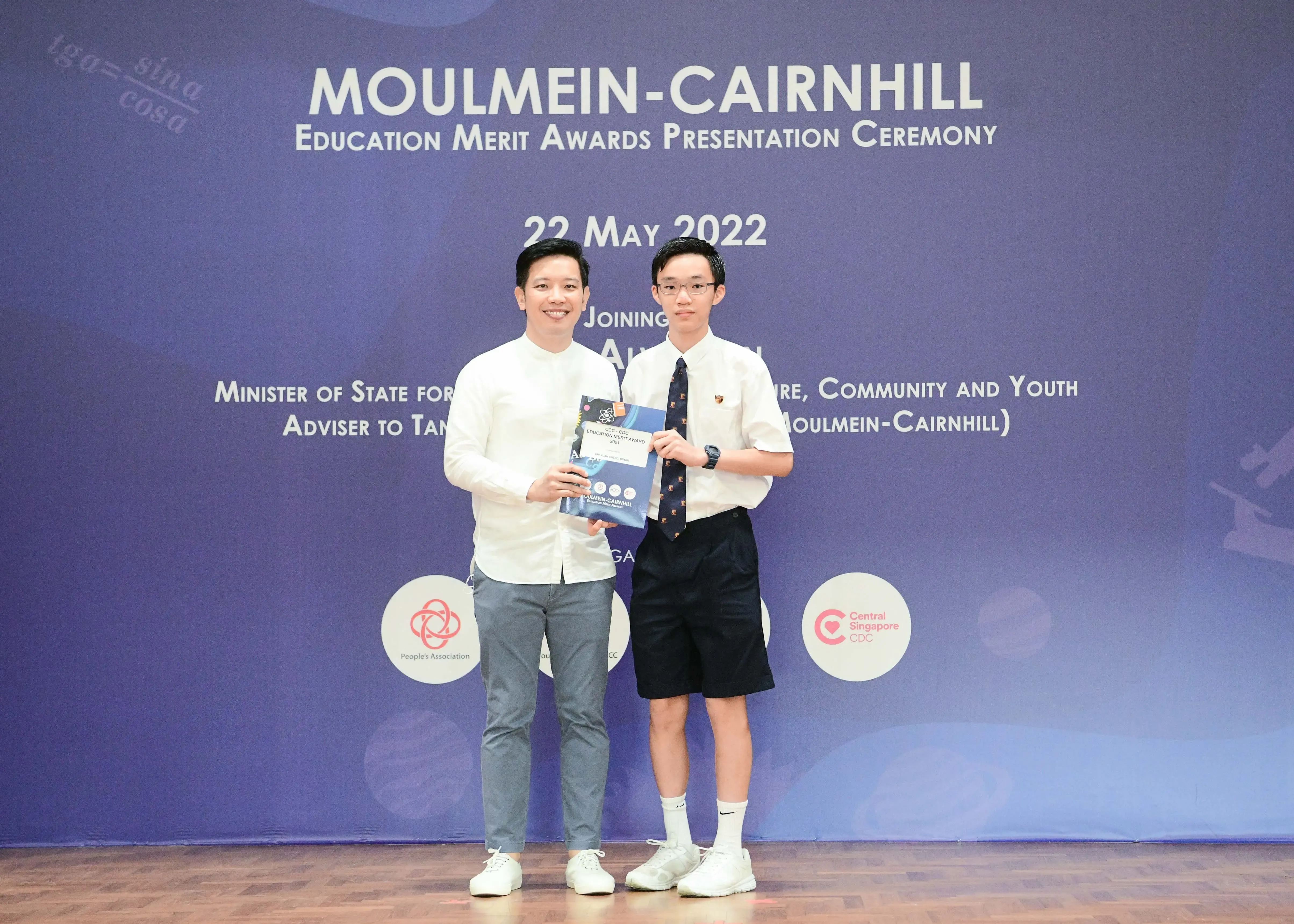 Two people hold an award certificate at the Moulmein-Cairnhill Education Merit Awards Presentation Ceremony on 22 May 2022.