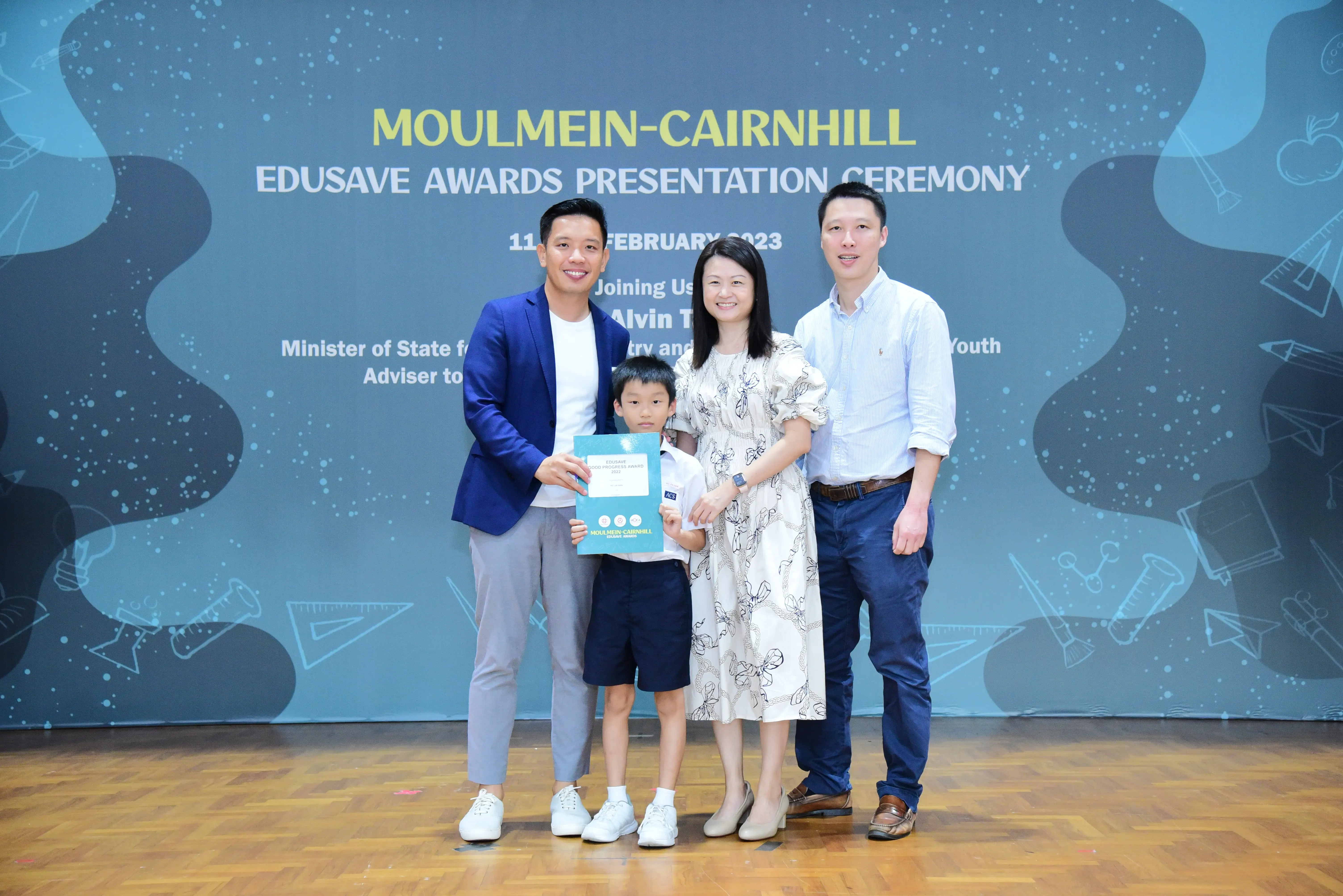 Three adults and a young boy pose at the Moulmein-Cairnhill Edusave Awards Presentation Ceremony in February 2023.