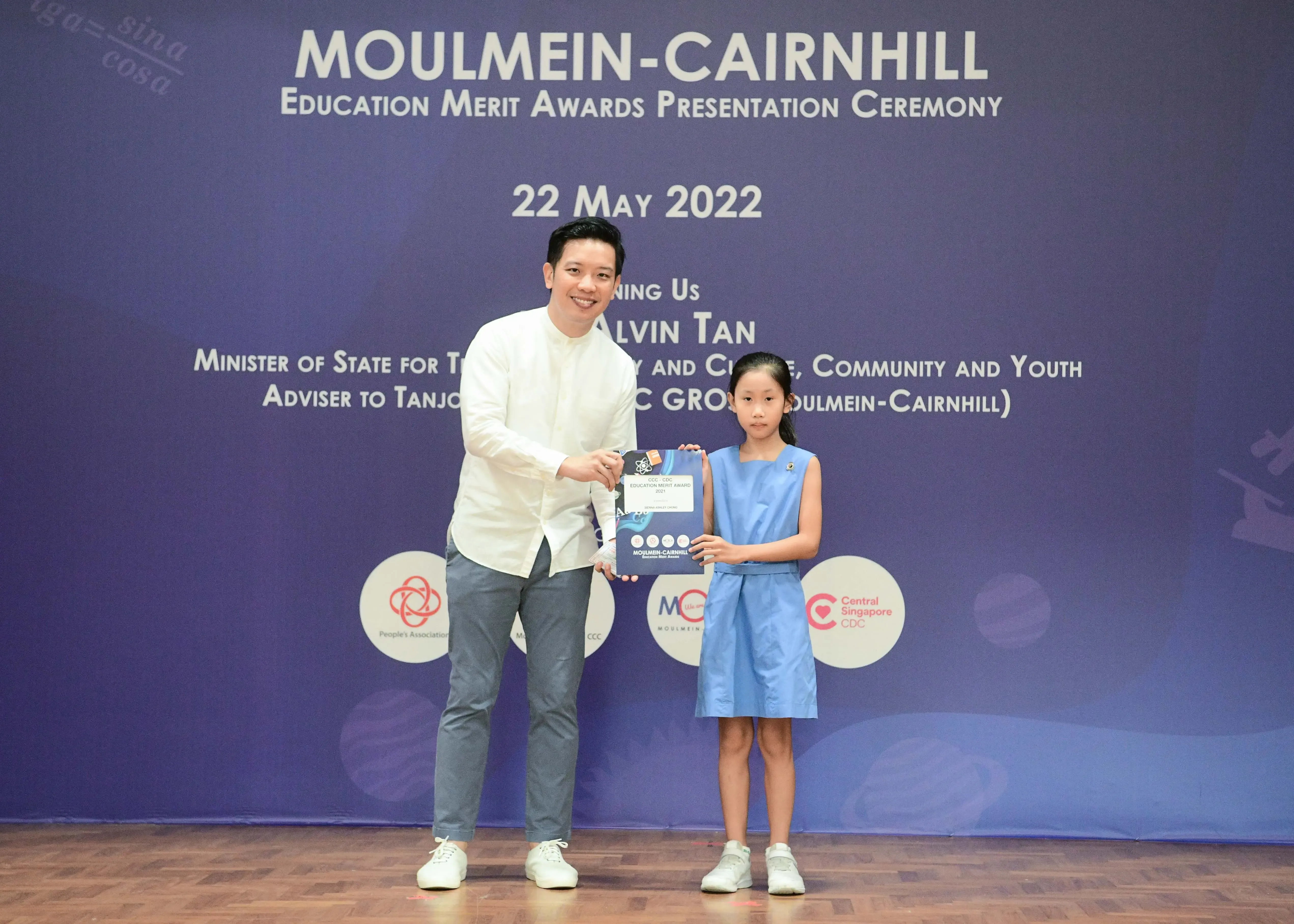A man and a young girl hold a certificate together at the Moulmein-Cairnhill Education Merit Awards on 22 May 2022.