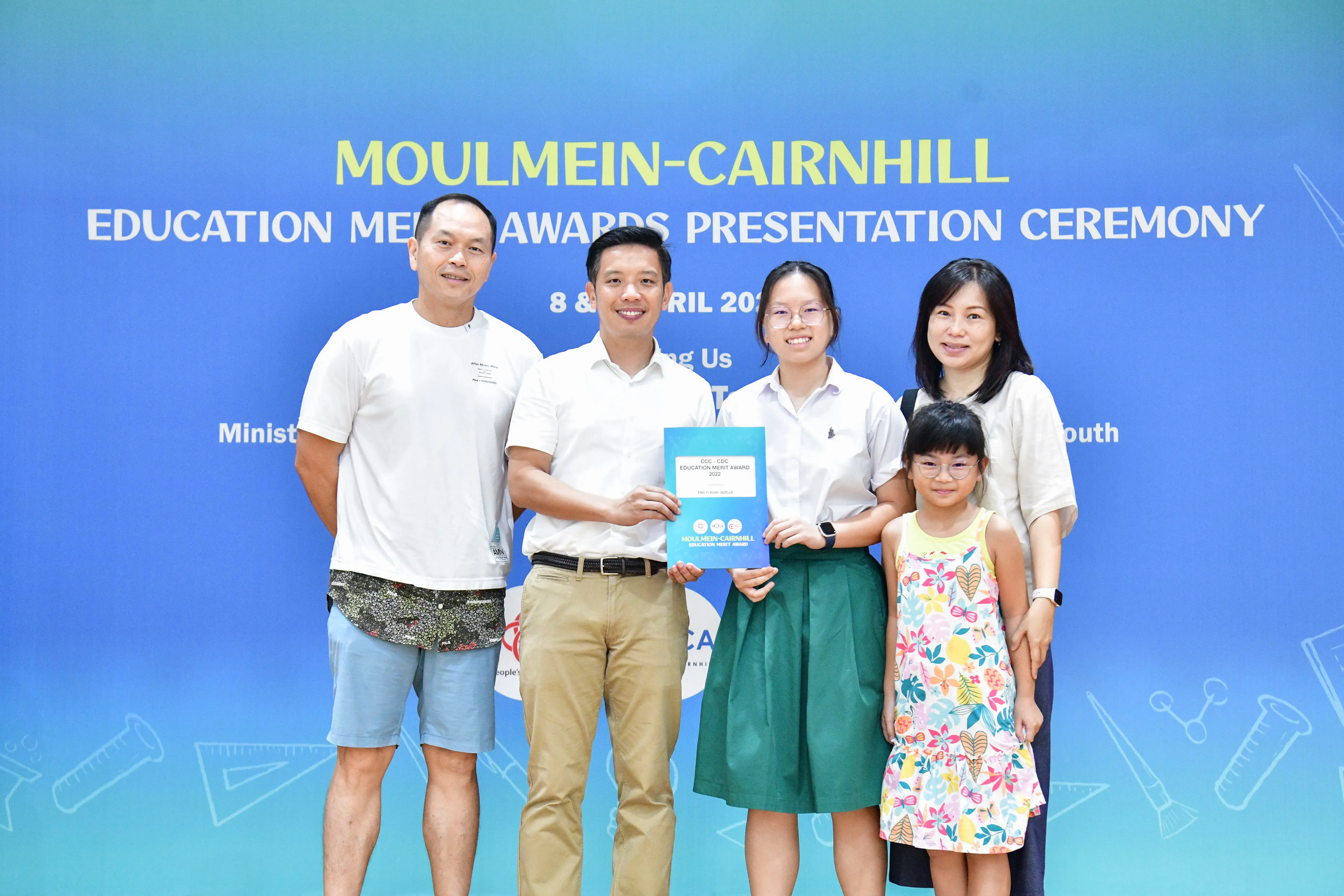 Five people pose at the Moulmein-Cairnhill Education Merit Awards Presentation Ceremony, holding a certificate.