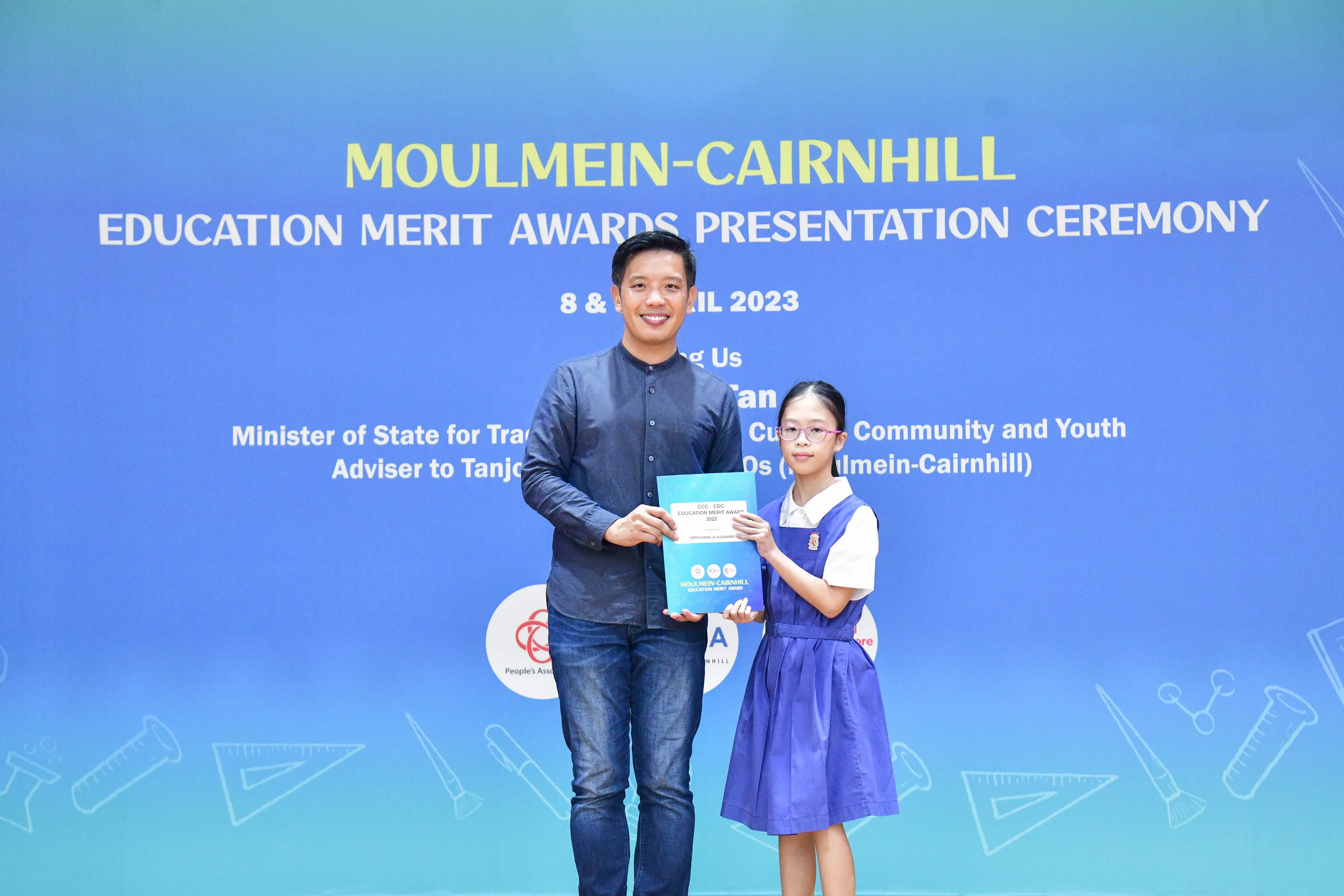 A man and a young girl in school uniform hold a certificate at the Moulmein-Cairnhill Education Merit Awards 2023.