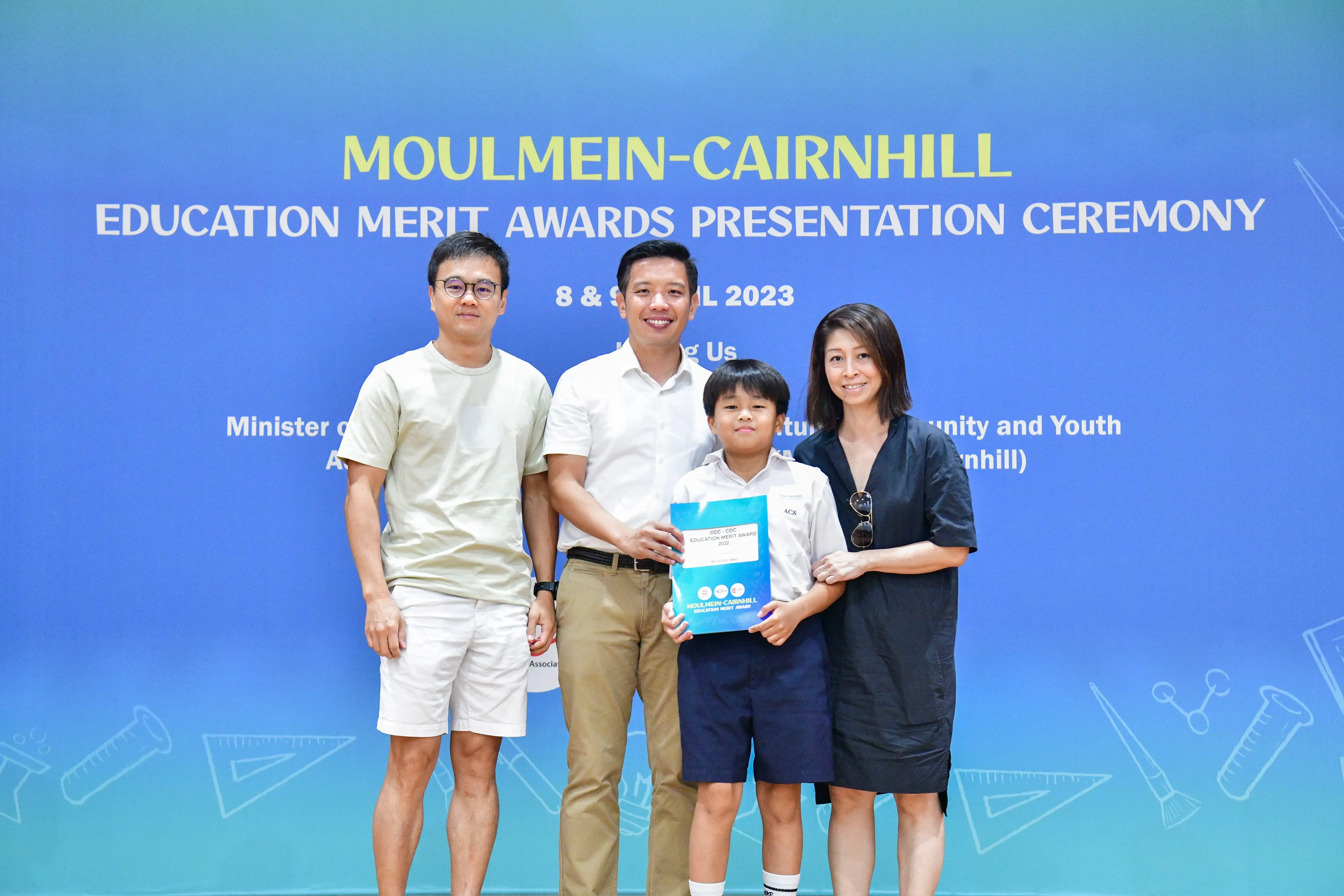 Three adults and a boy holding an award folder pose at the Moulmein-Cairnhill Education Merit Awards 2023.