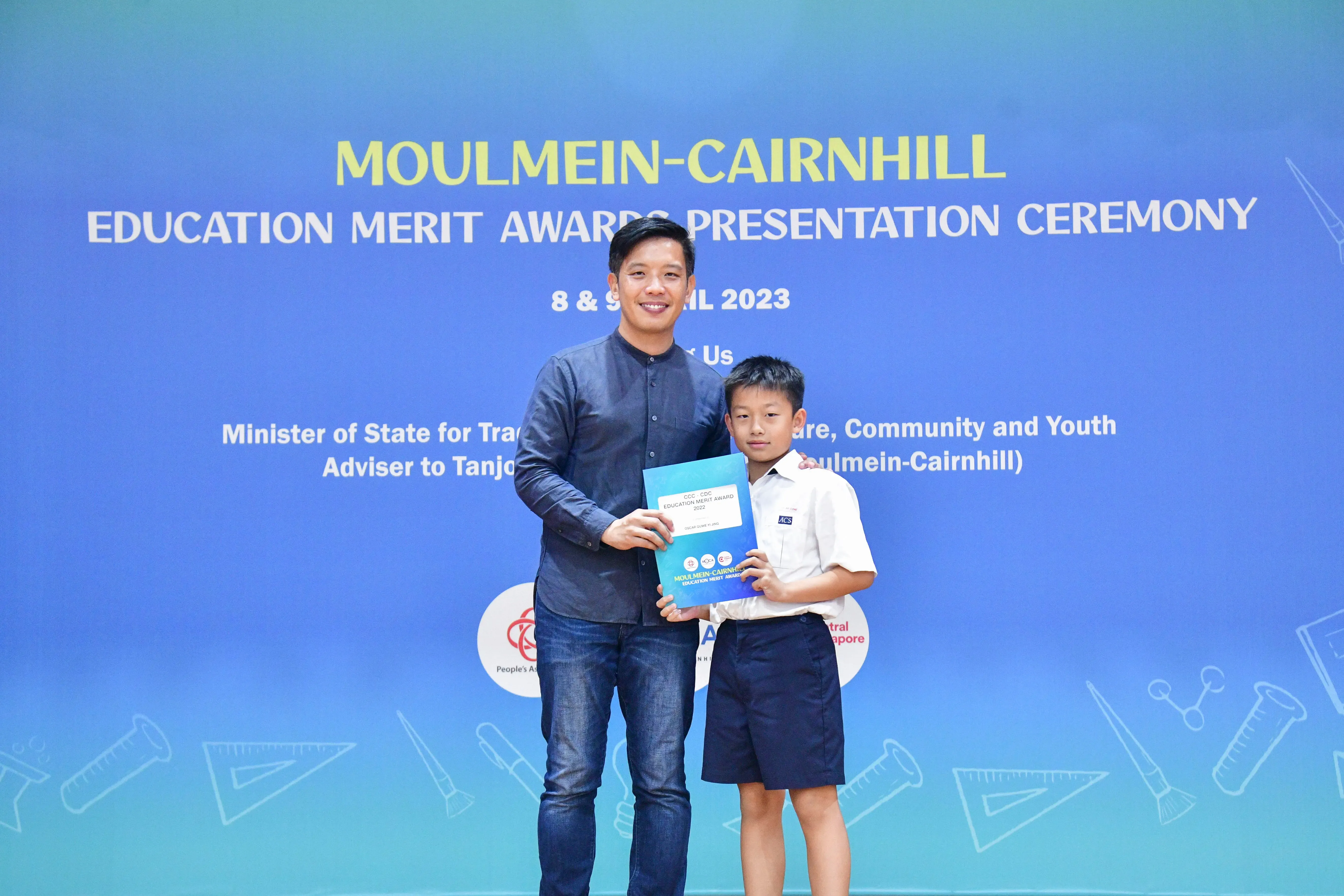 A man and a young boy hold a certificate together at the Moulmein-Cairnhill Education Merit Awards Ceremony 2023.