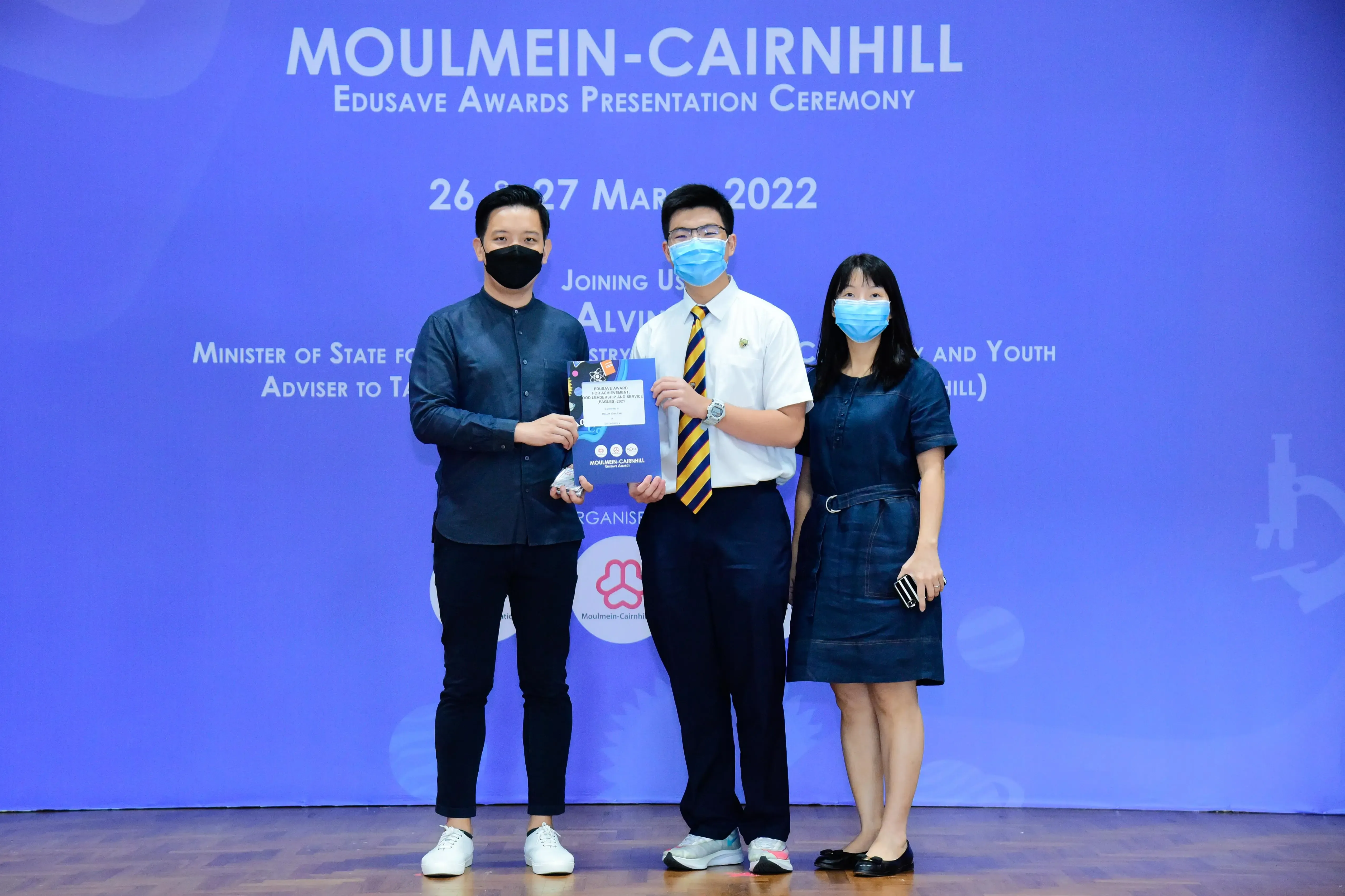 Three masked people pose at the Moulmein-Cairnhill Edusave Awards Presentation Ceremony on 26-27 March 2022.