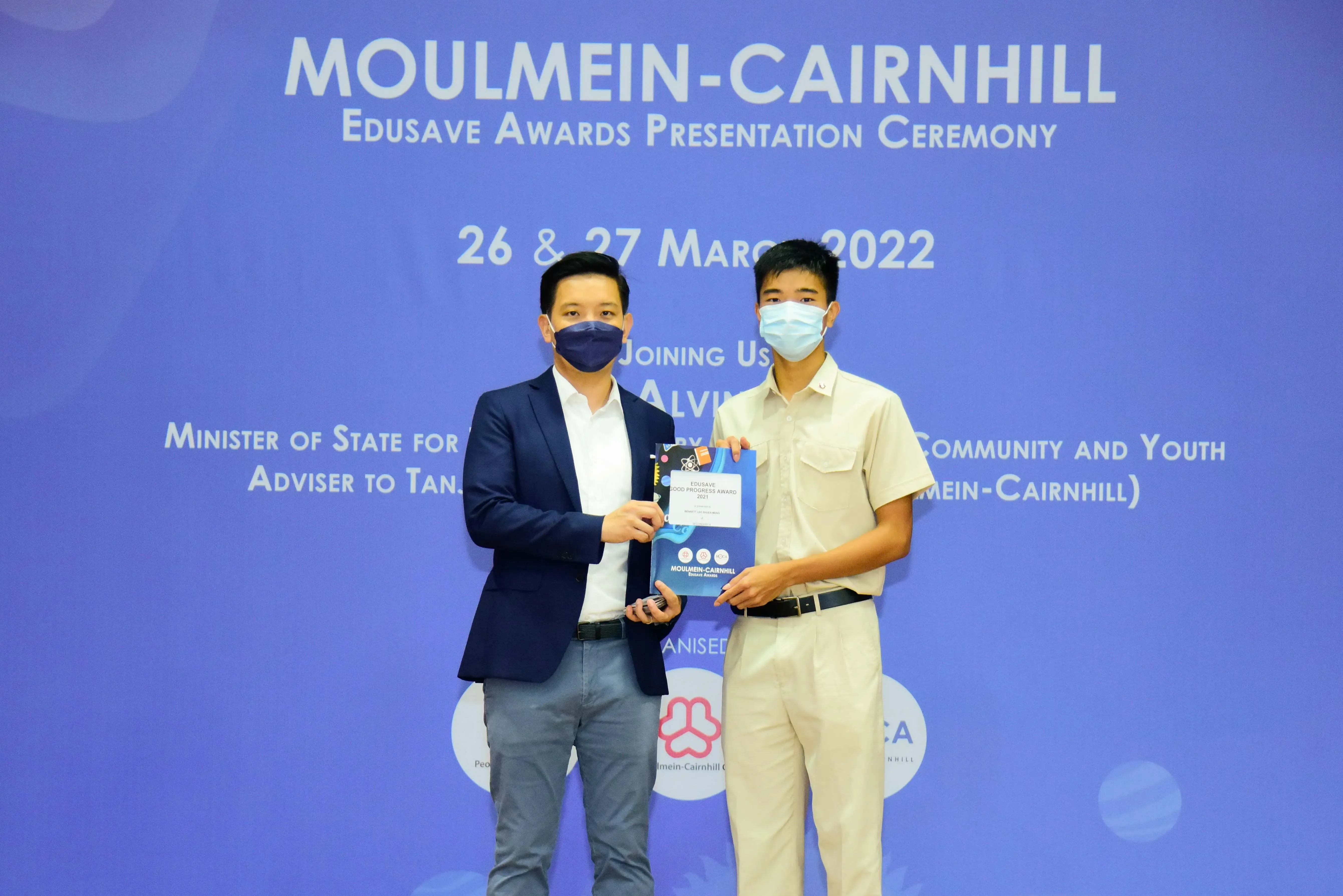 Two masked men hold an Edusave award certificate at the Moulmein-Cairnhill Edusave Awards Ceremony, March 2022.