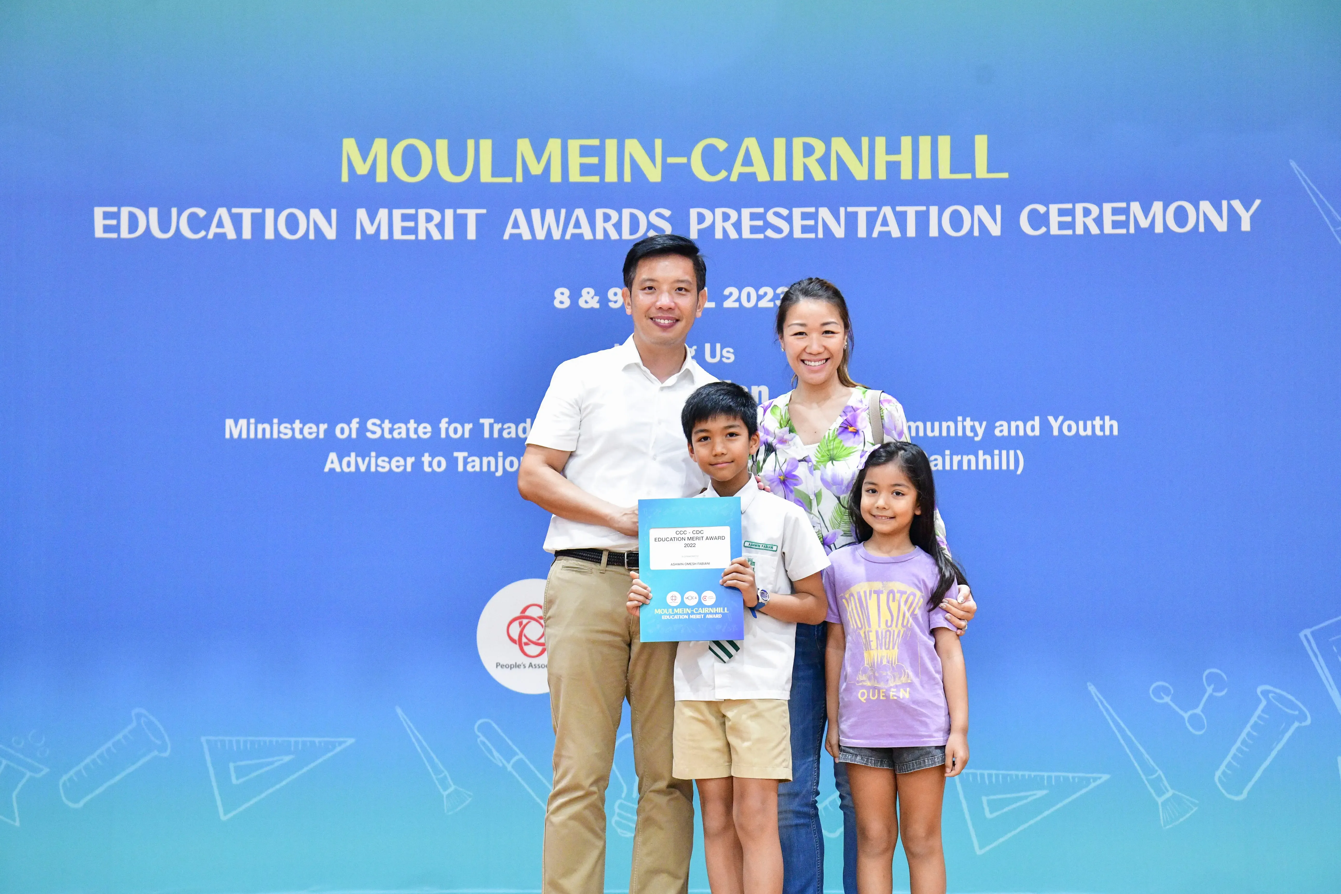 Family of four posing at the Moulmein-Cairnhill Education Merit Awards Presentation Ceremony, boy holding an award certificate.